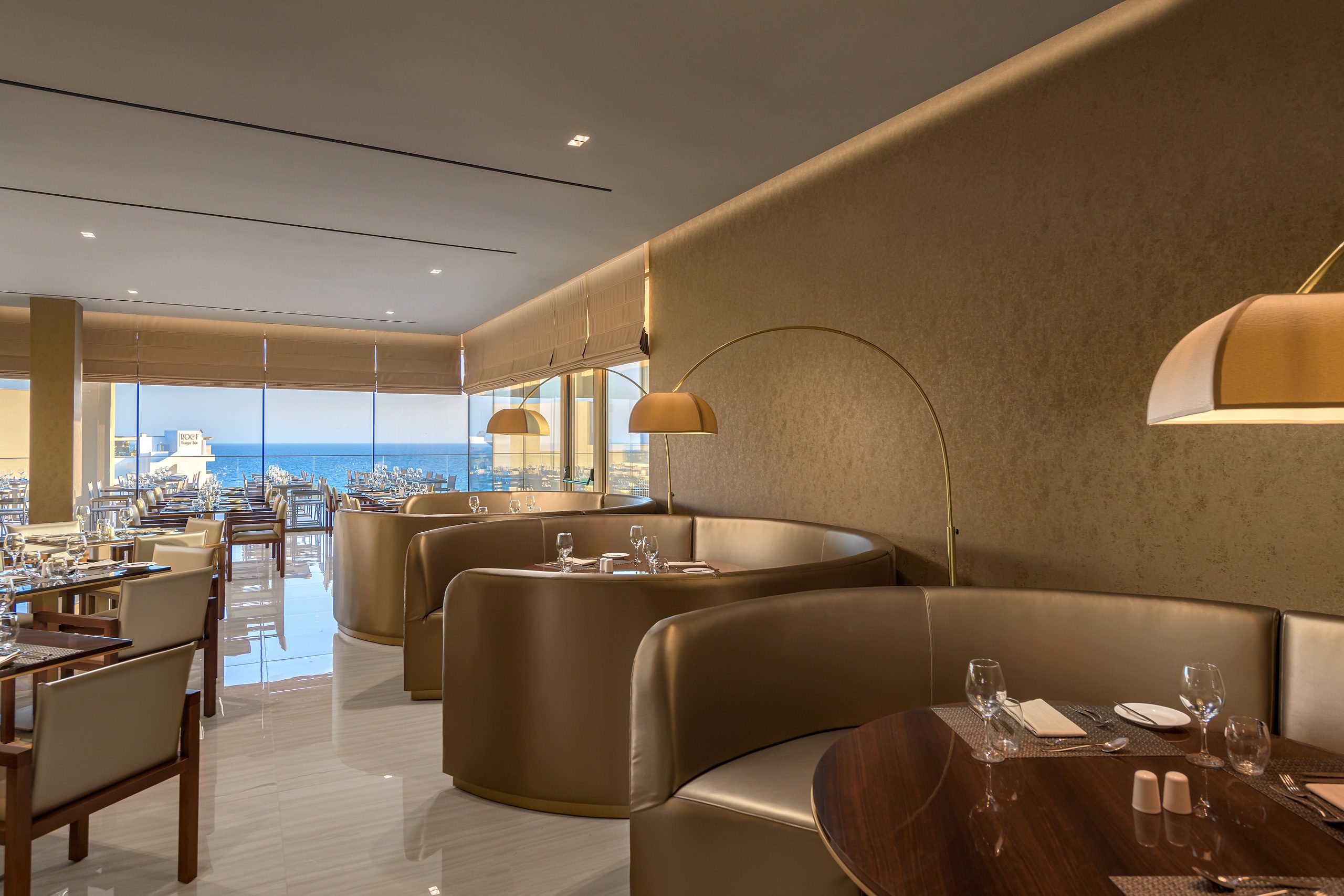 Modern lounge area with curved brown sofas and large windows.