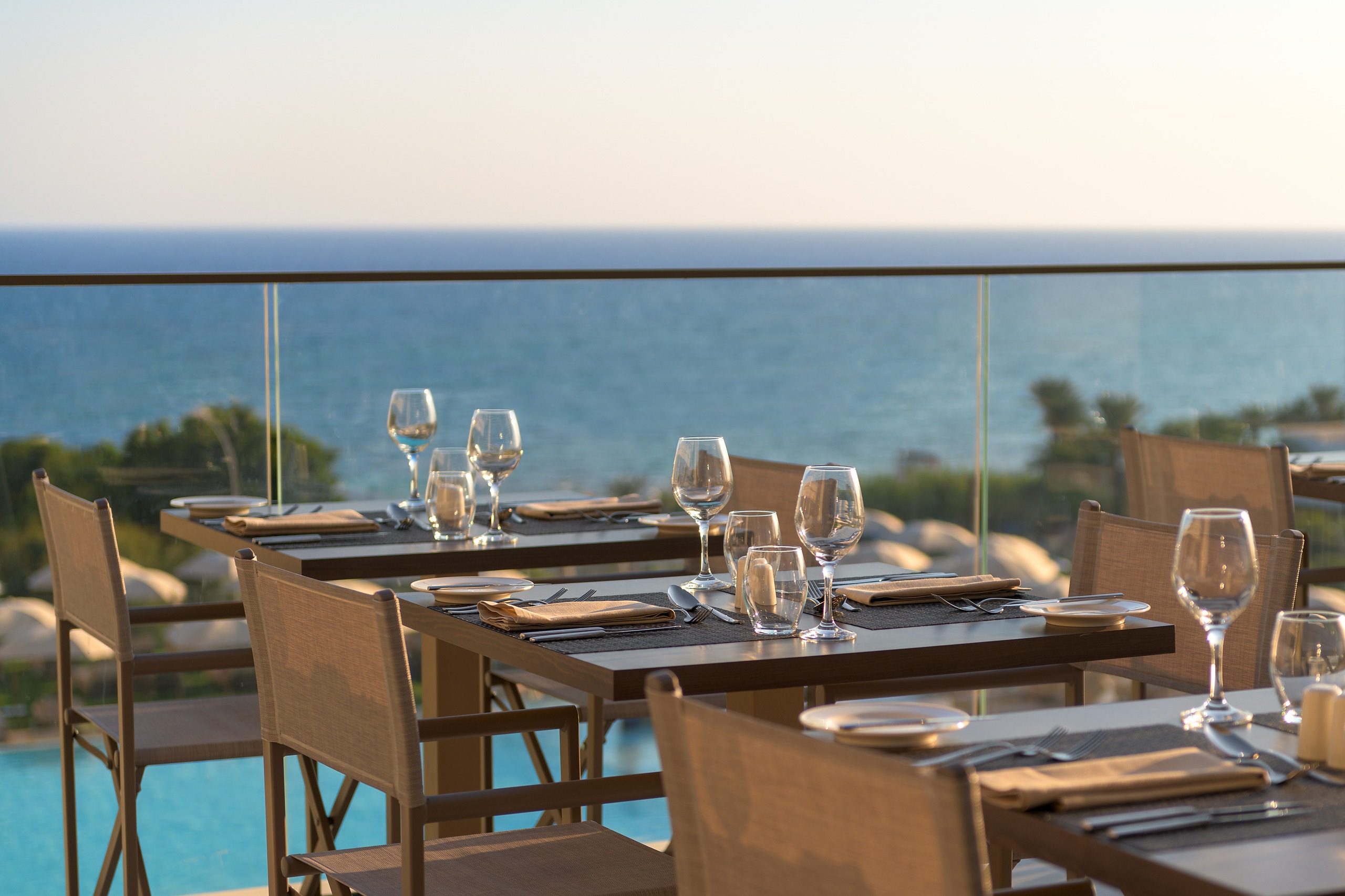 Elegant outdoor dining setup overlooking the ocean at sunset.