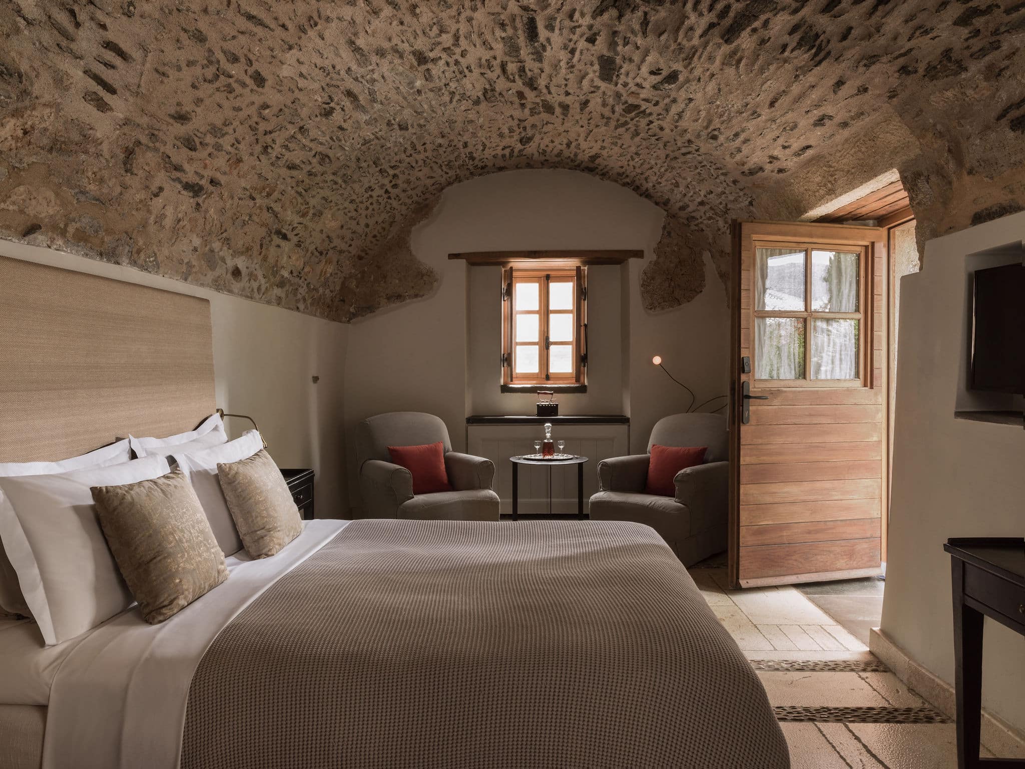 Cozy rustic bedroom with stone walls and warm lighting.
