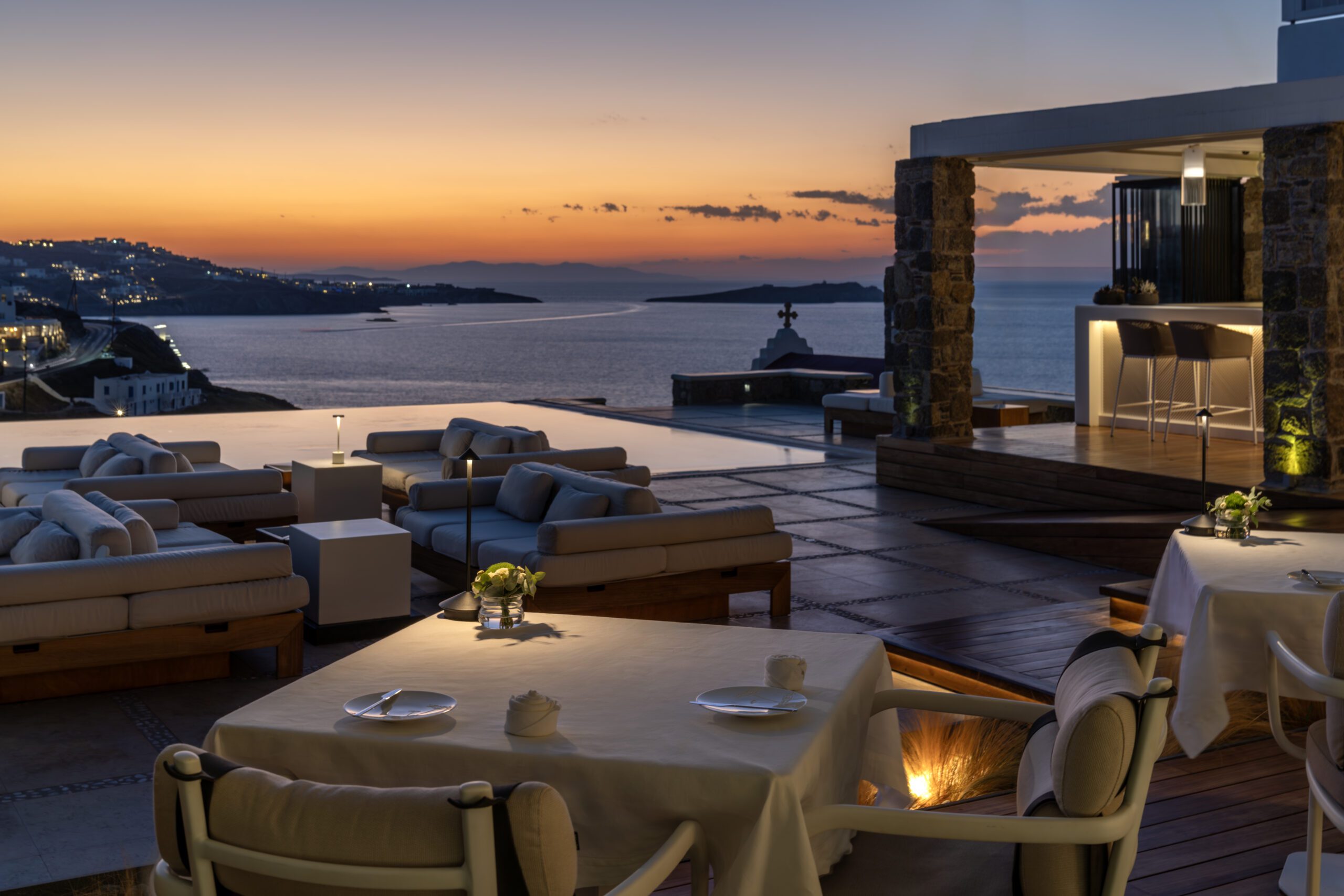 Elegant outdoor dining with sunset sea views and cozy seating.