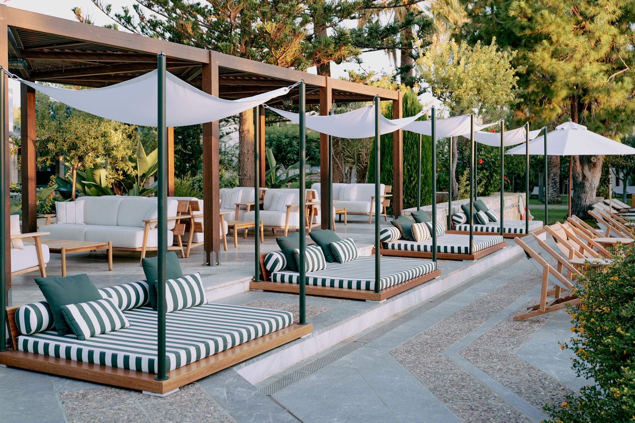 Outdoor lounge area with cushioned swinging seats and triangular sunshades.