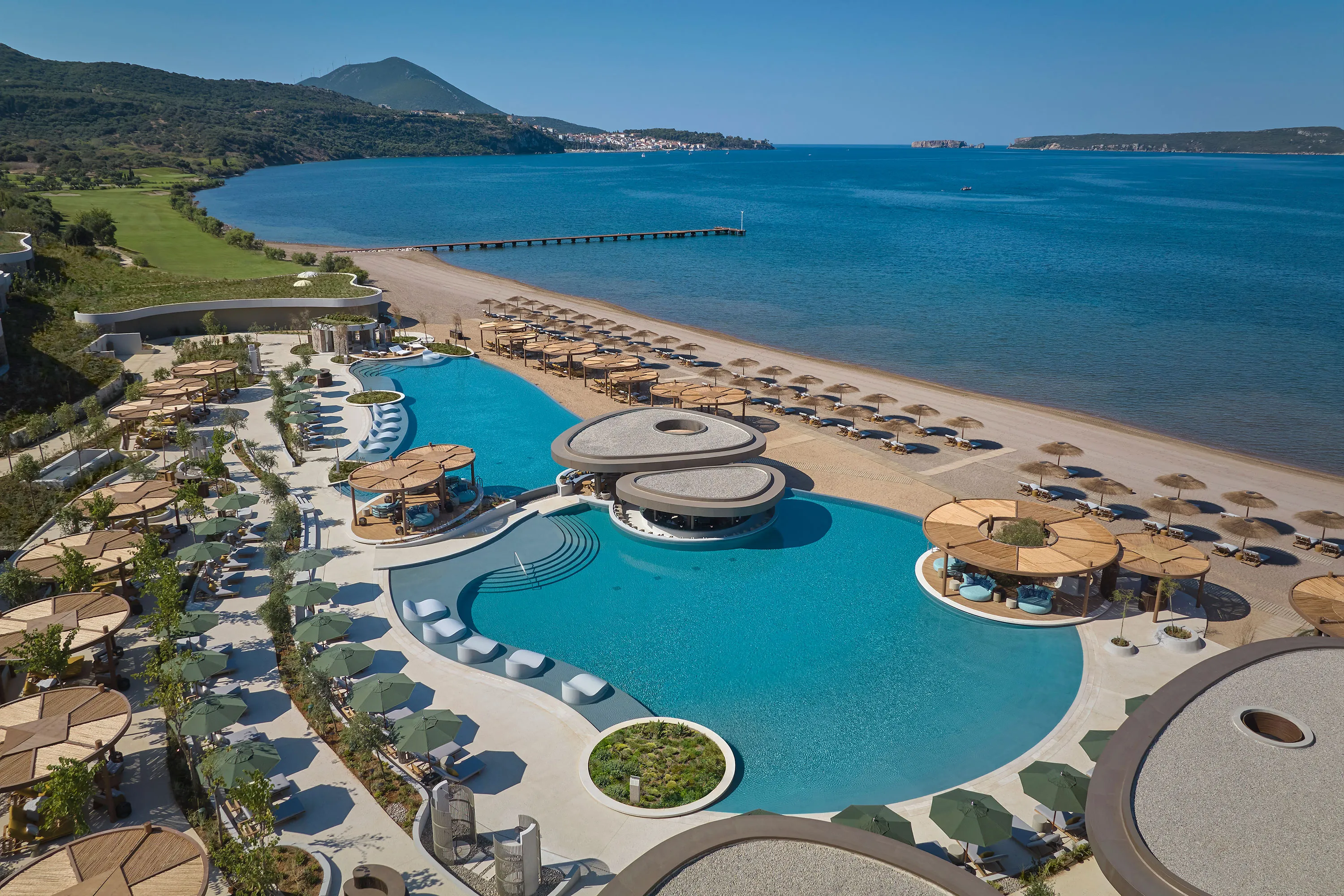 A luxurious beachfront resort with pools and sun loungers under umbrellas.