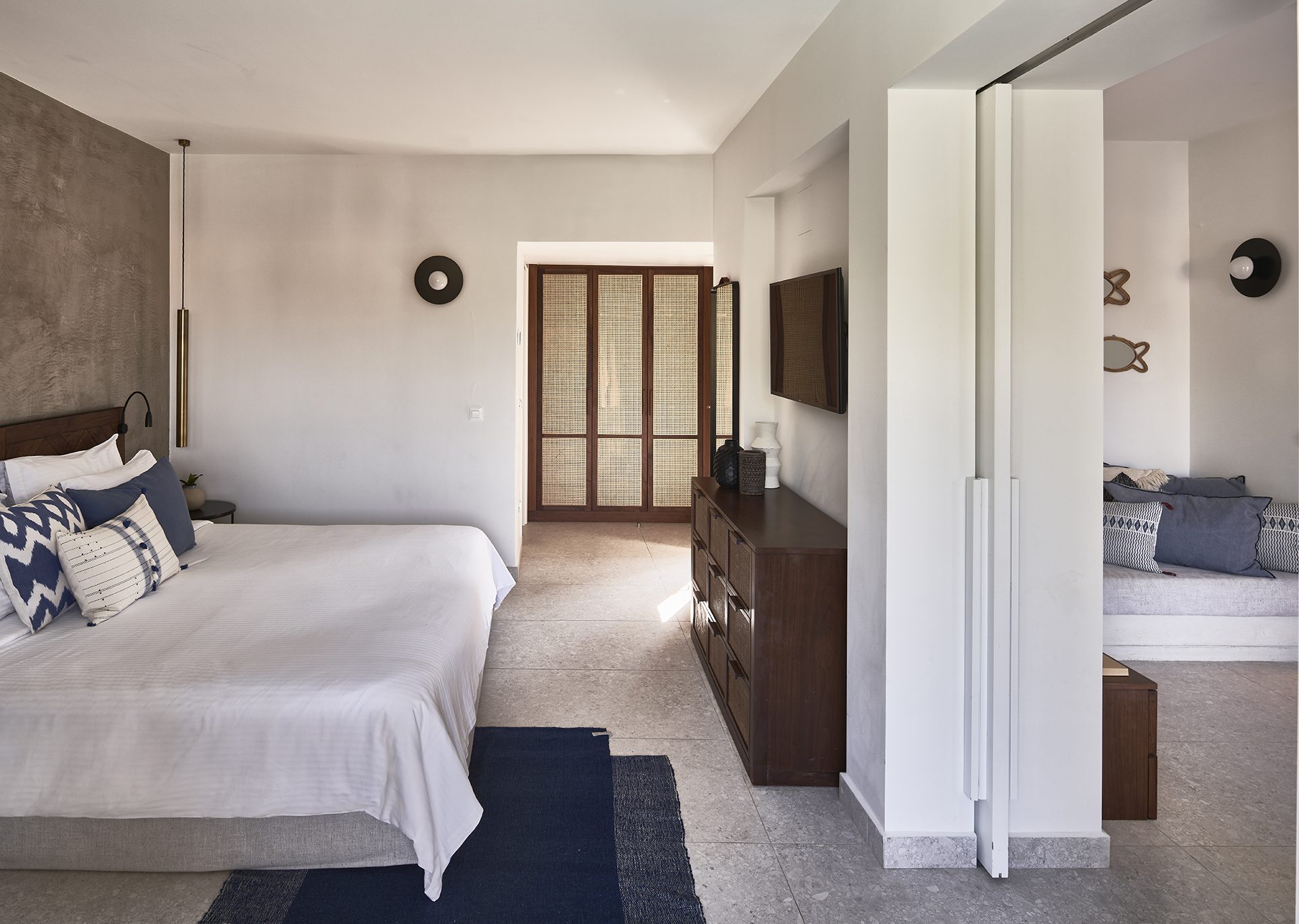 Minimalist bedroom with white linens and natural light from wooden windows.