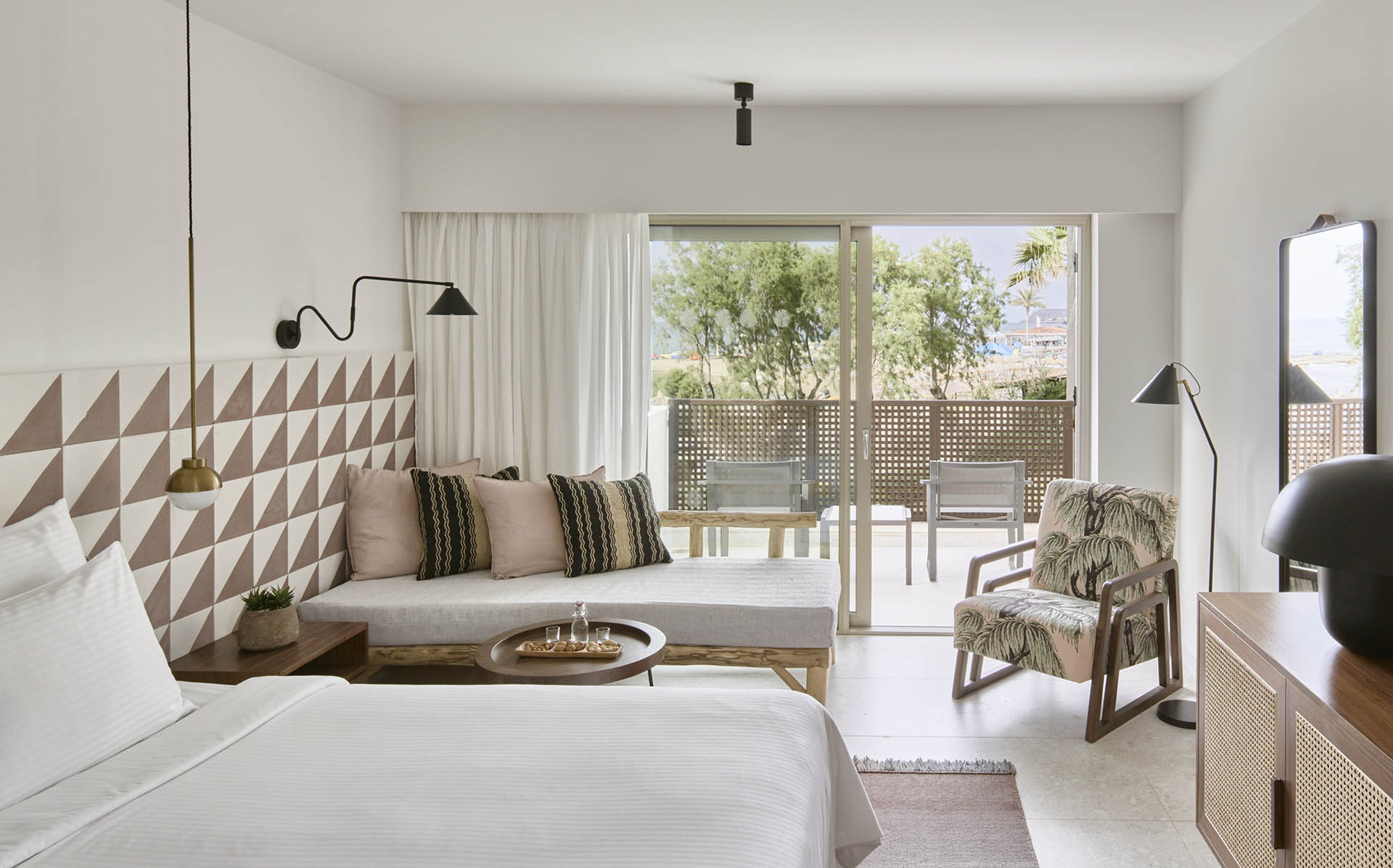 Bright, modern hotel room with a balcony and cozy seating.