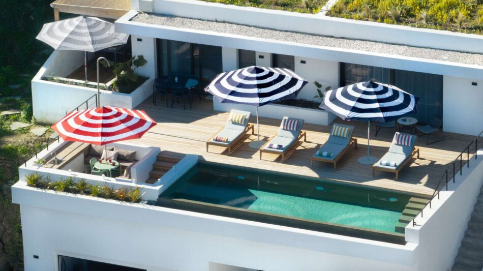 Poolside lounge area with striped umbrellas and sunbeds.