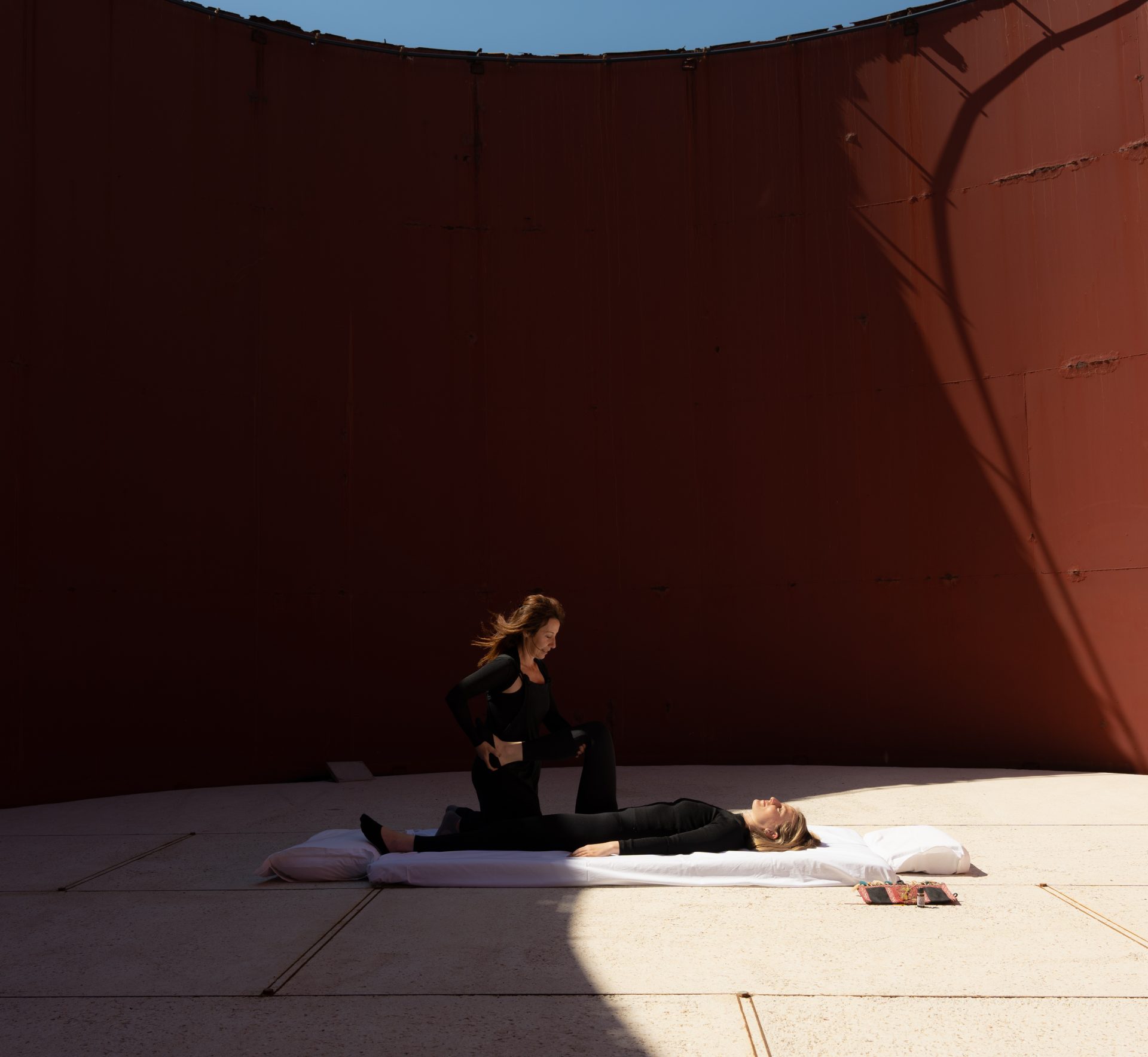 A person practicing yoga inside a large red-walled circular structure.
