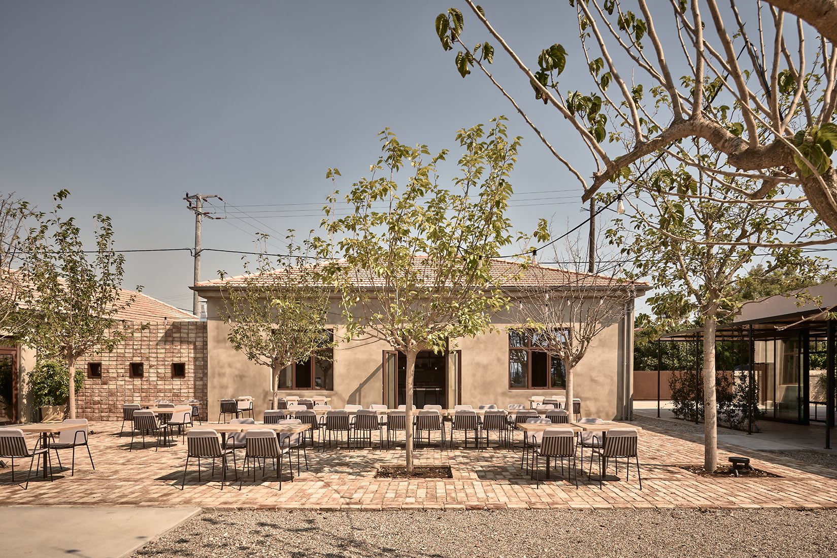 Abandoned stone building with scattered bricks and dry trees around.