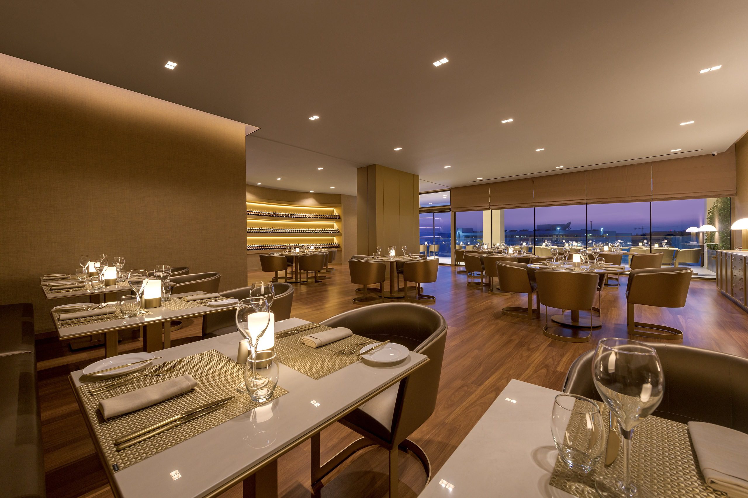 Elegant restaurant interior with city skyline views at dusk.