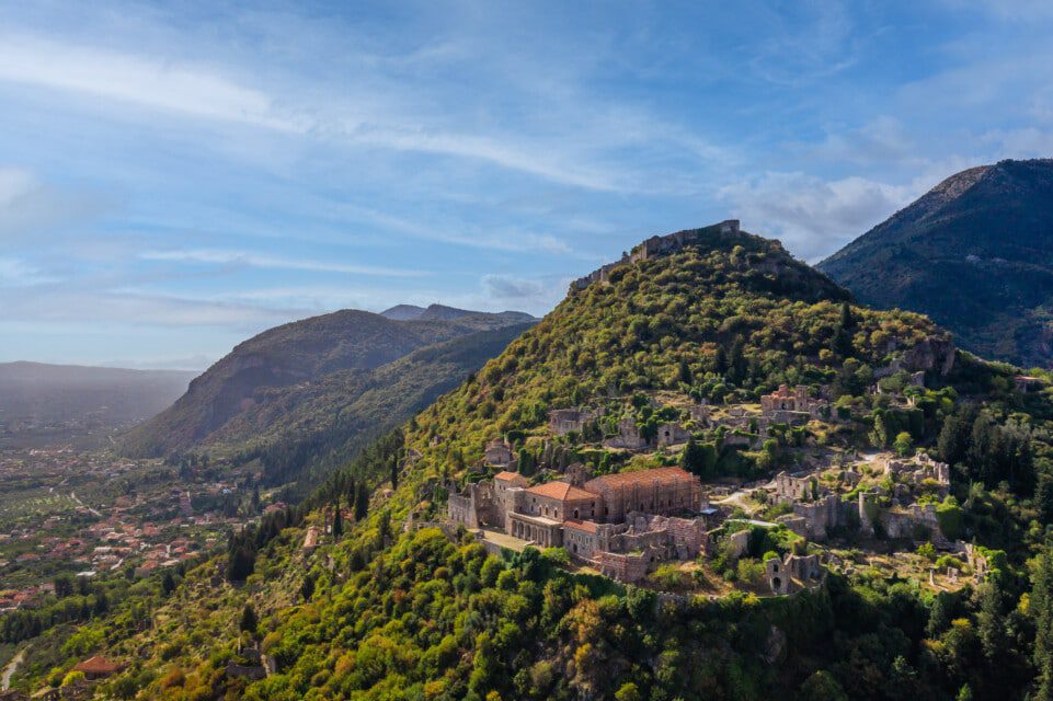 A monastery nestled on a green hillside under a blue sky.