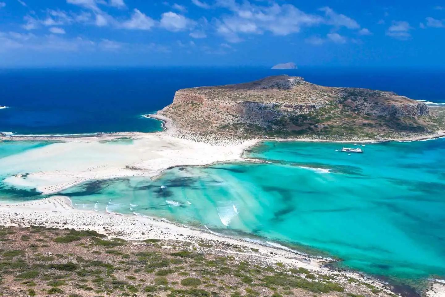 A stunning turquoise lagoon with white sandy beaches under a blue sky.