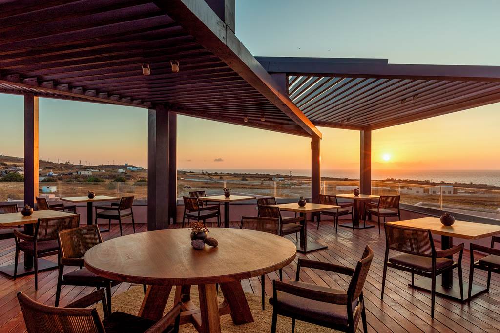 Sunset dining area with wooden tables and chairs on a rooftop.