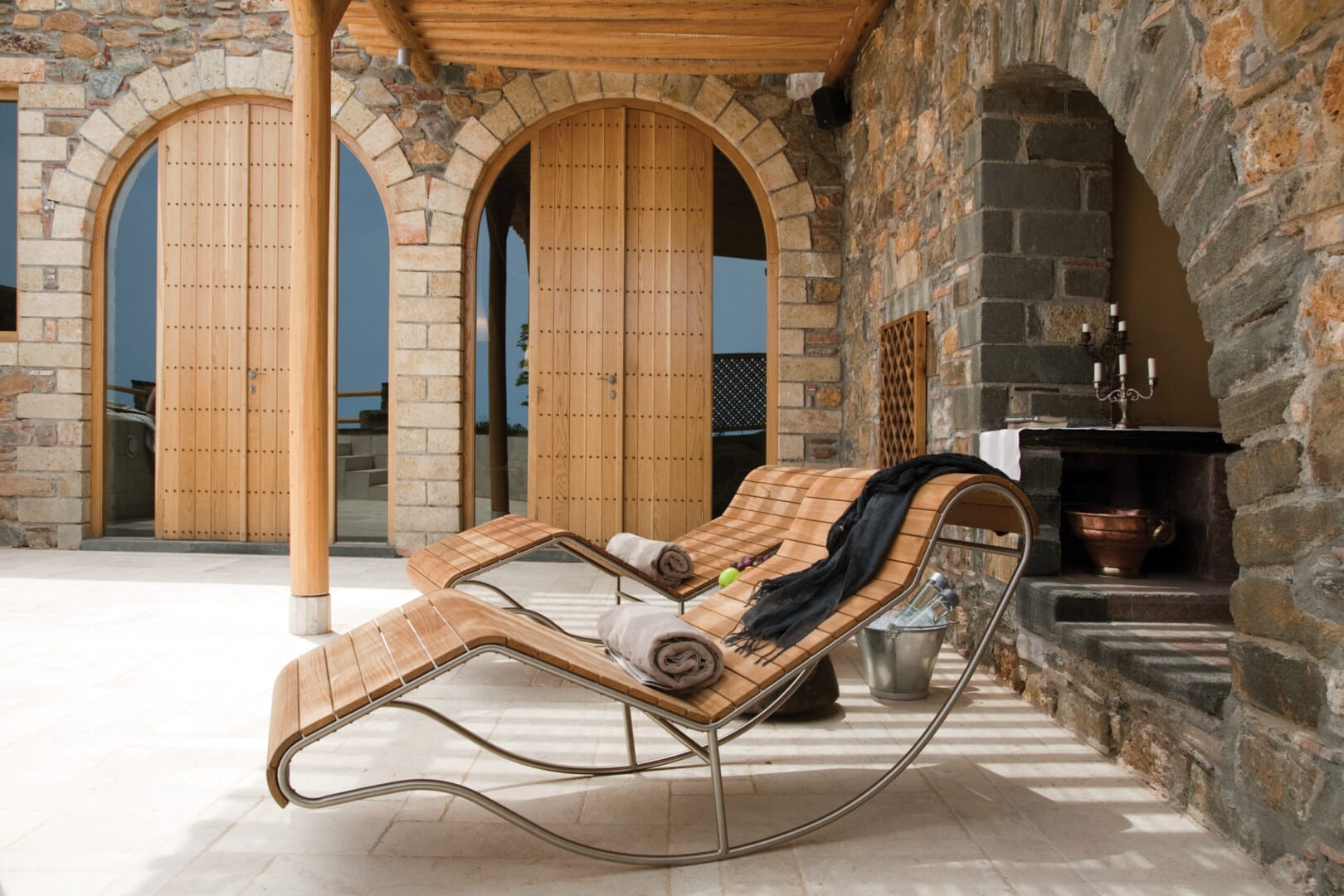 Modern lounge chair in a rustic stone room with wooden accents.