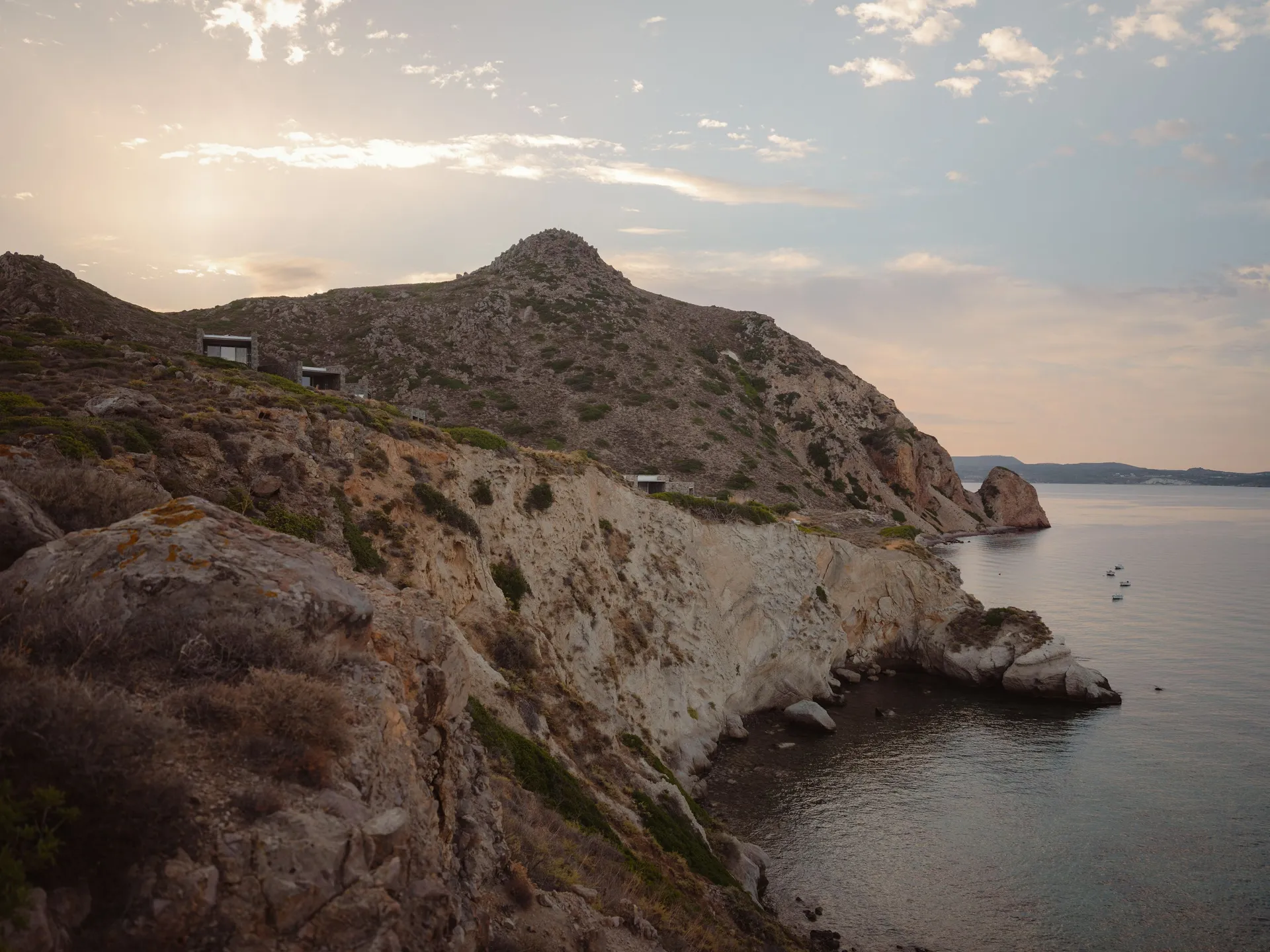 Rocky coastal cliff under a cloudy sky at sunset.