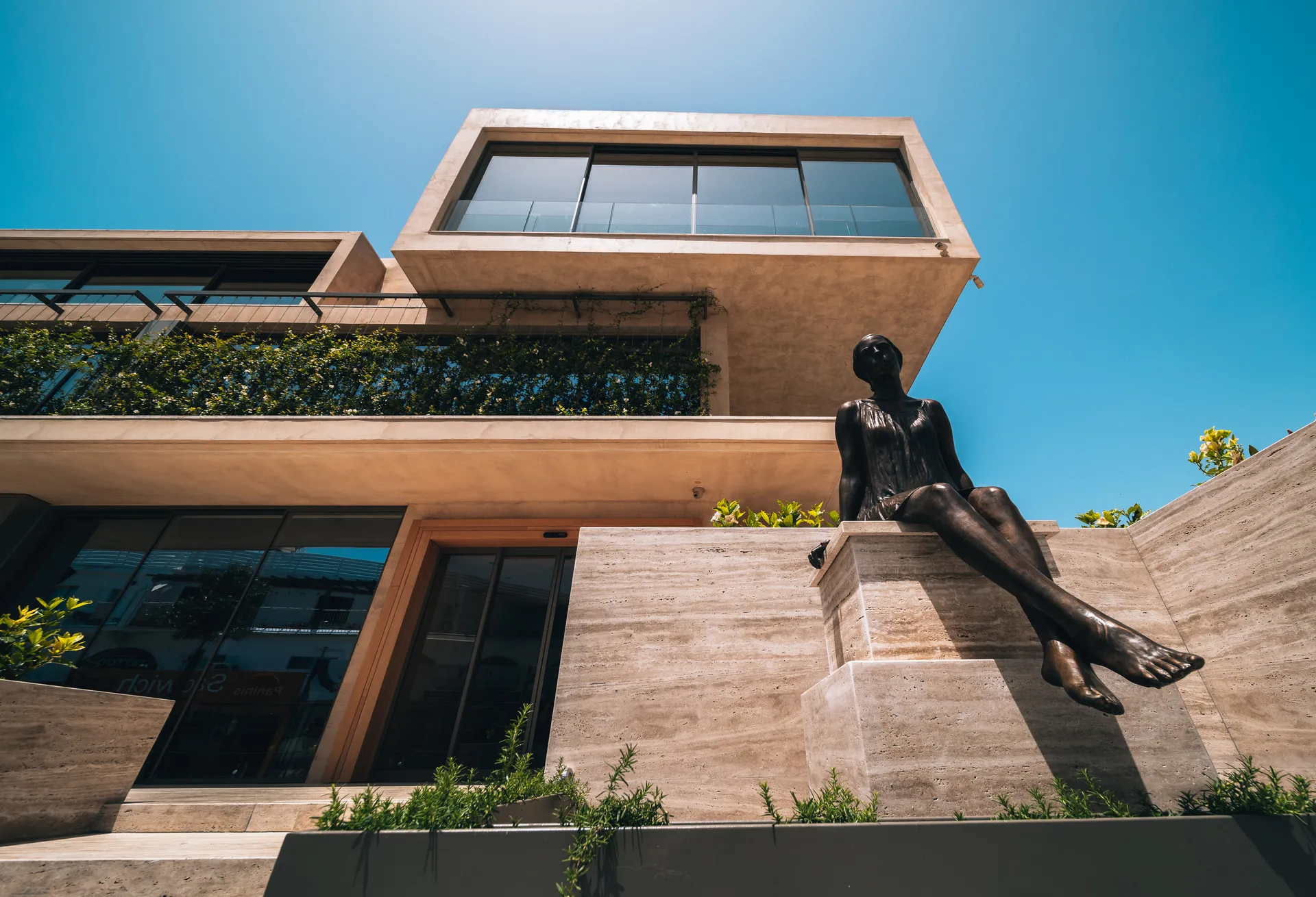 Modern building with a statue against a clear blue sky.