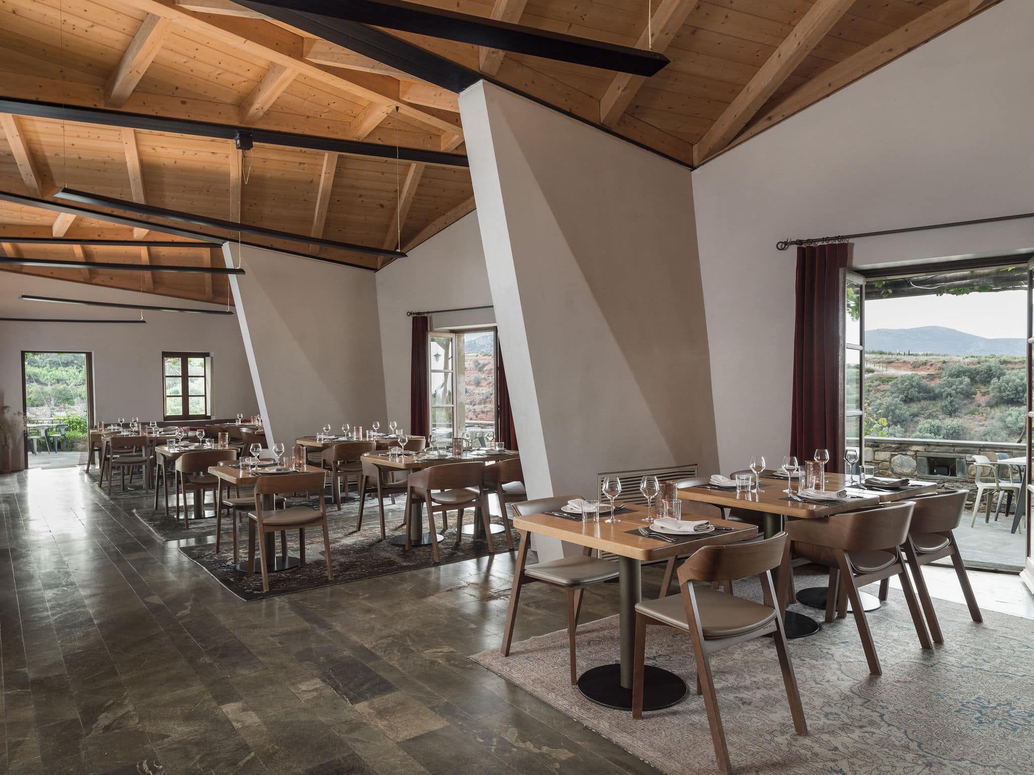 Modern restaurant interior with wooden ceiling and neatly set tables.