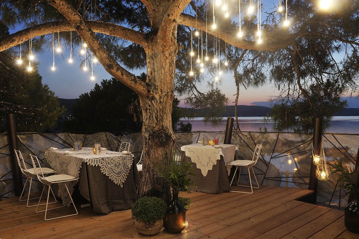 Cozy outdoor dining area with string lights and wooden deck at dusk.