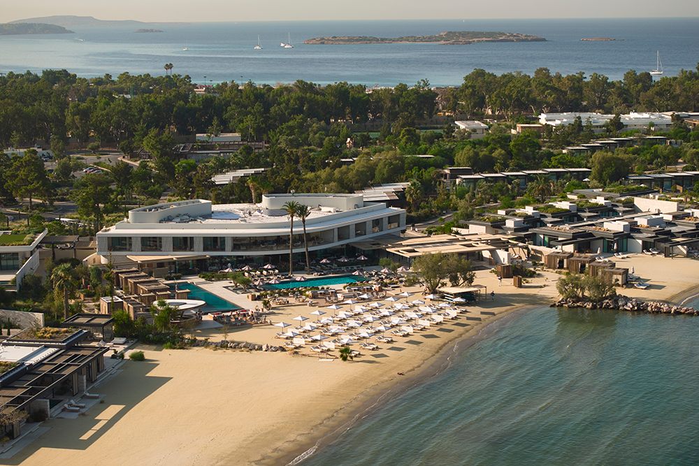 A beach resort with lounge chairs and umbrellas by the shoreline.