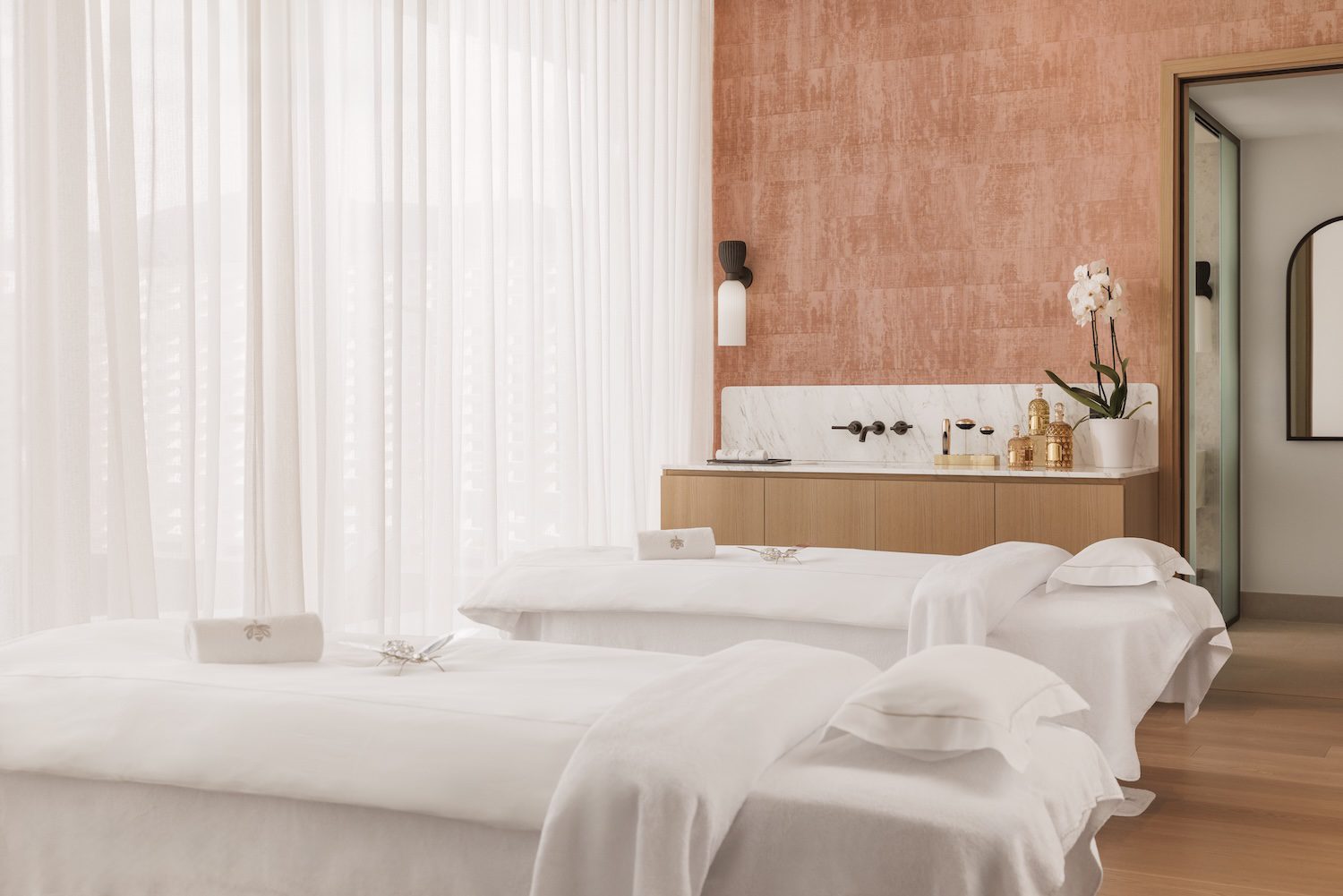 Minimalist spa room with two massage tables and soft natural light.