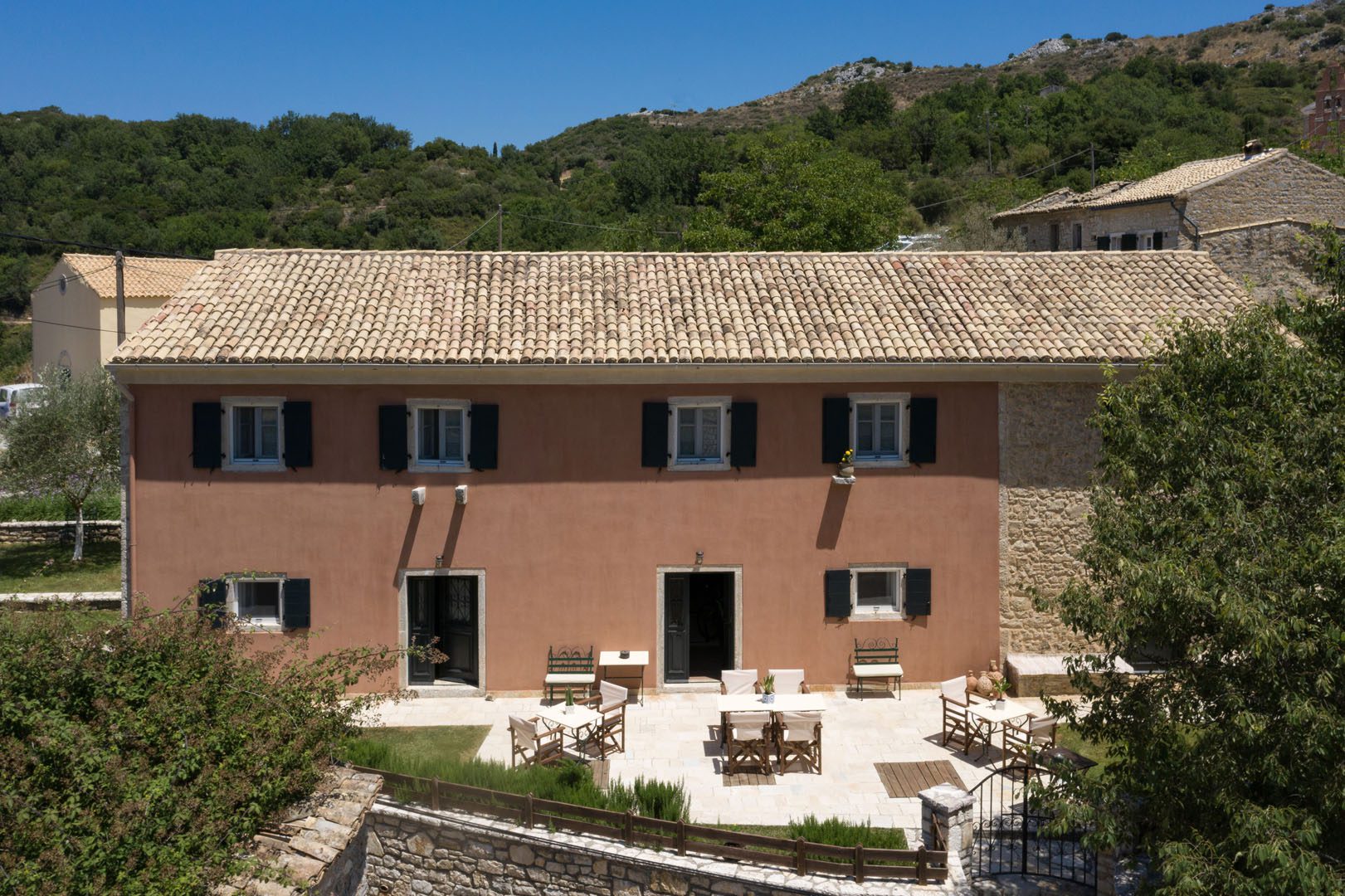 Charming rustic villa with outdoor seating surrounded by greenery.
