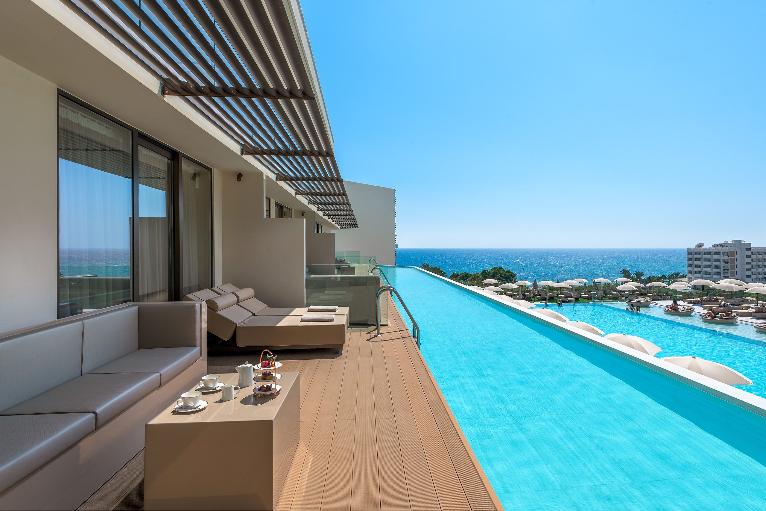 Luxurious infinity pool with ocean view and modern patio seating.
