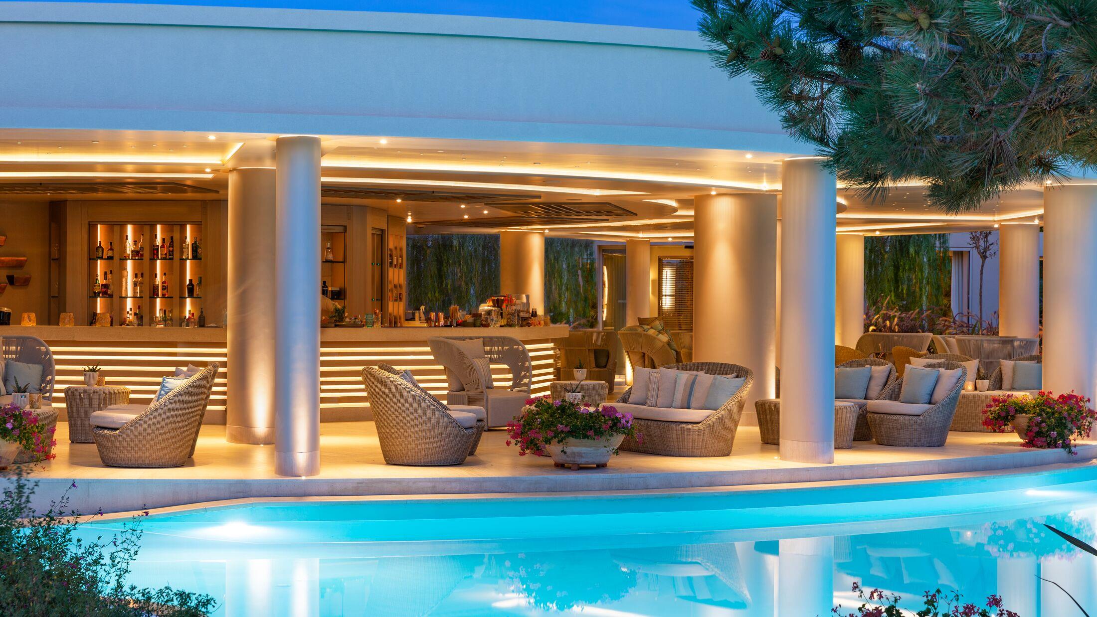 Luxurious outdoor seating area by an illuminated pool at night.