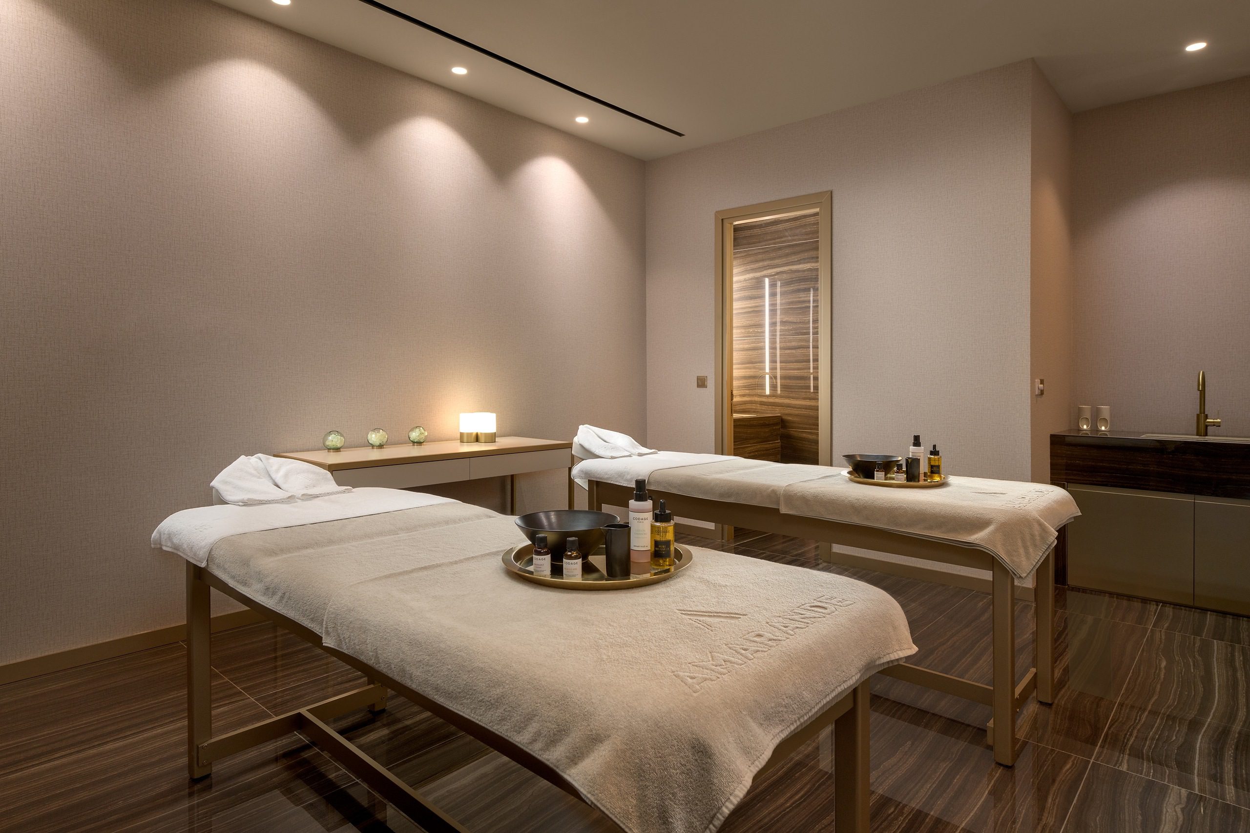 A serene spa room with two massage tables and soft lighting.