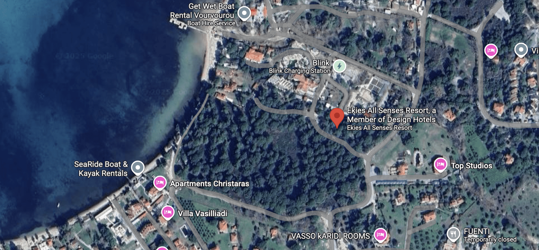 Aerial view of a forested area near a coast with marked locations for a Christmas event and a chapel.