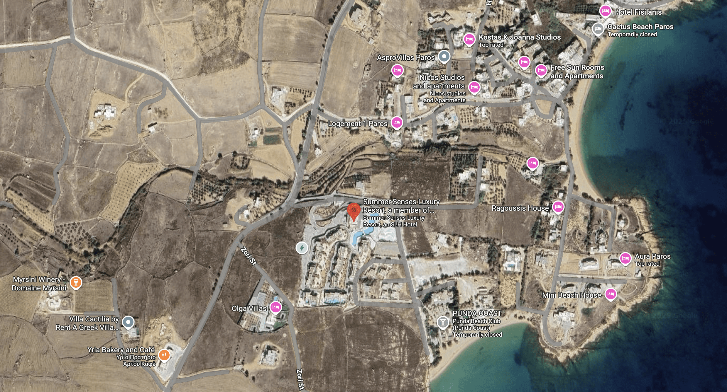 A satellite view of a coastal area with buildings and roads.