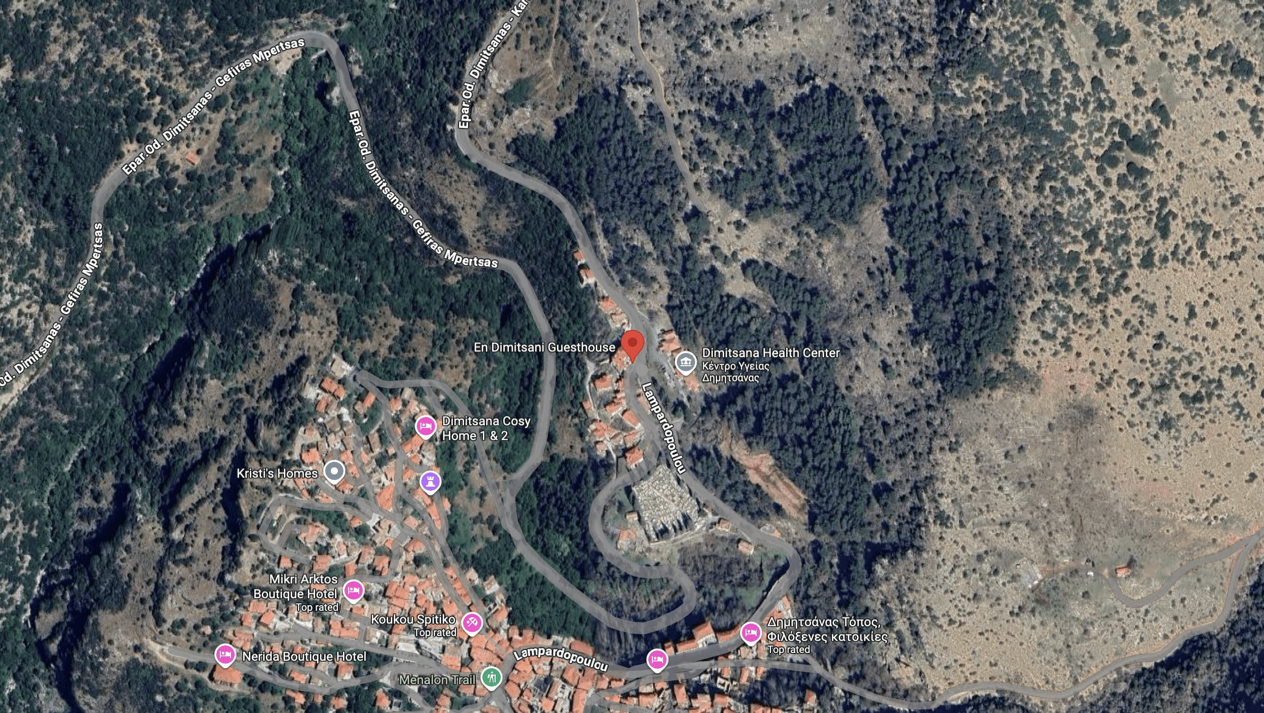 A winding river flowing through a forested hilly area with scattered buildings.