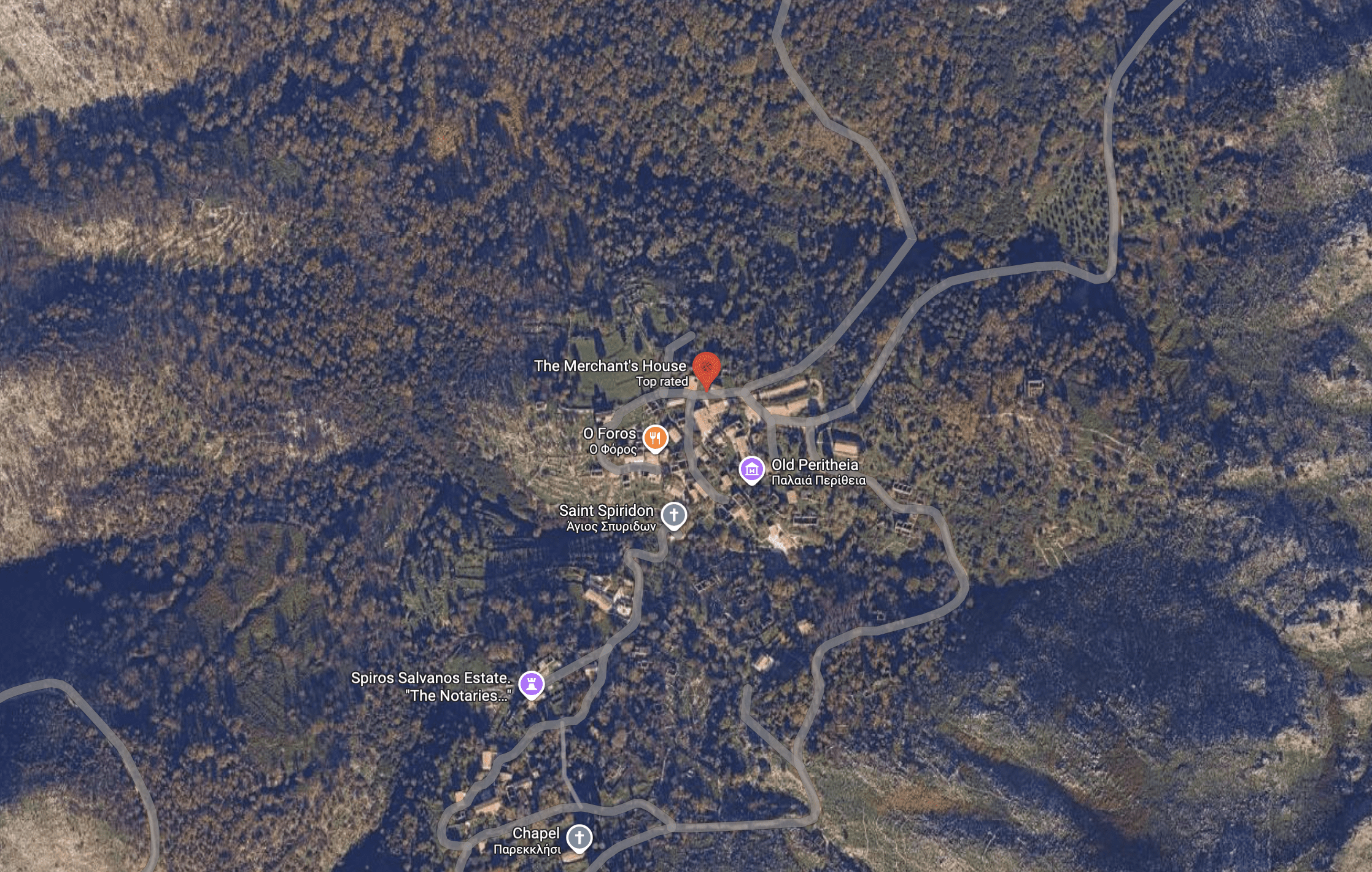 A satellite view of a small town nestled in wooded hills with a winding river.