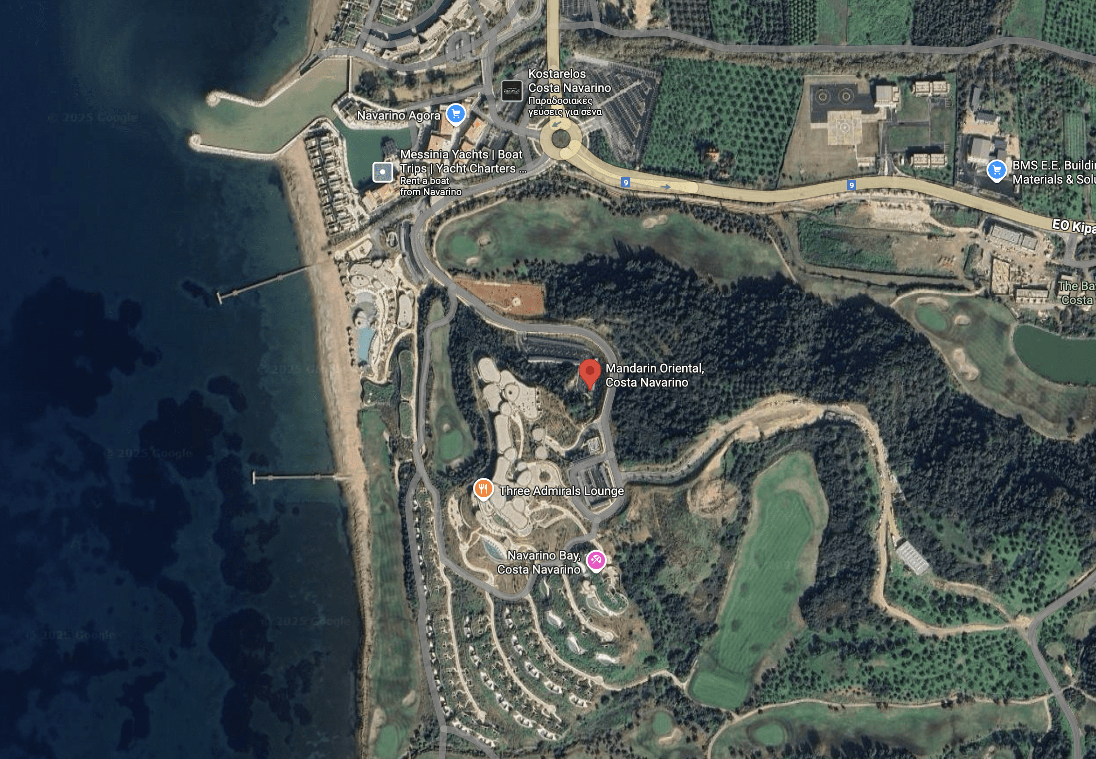 Aerial view of a coastal resort with winding roads and green hills.