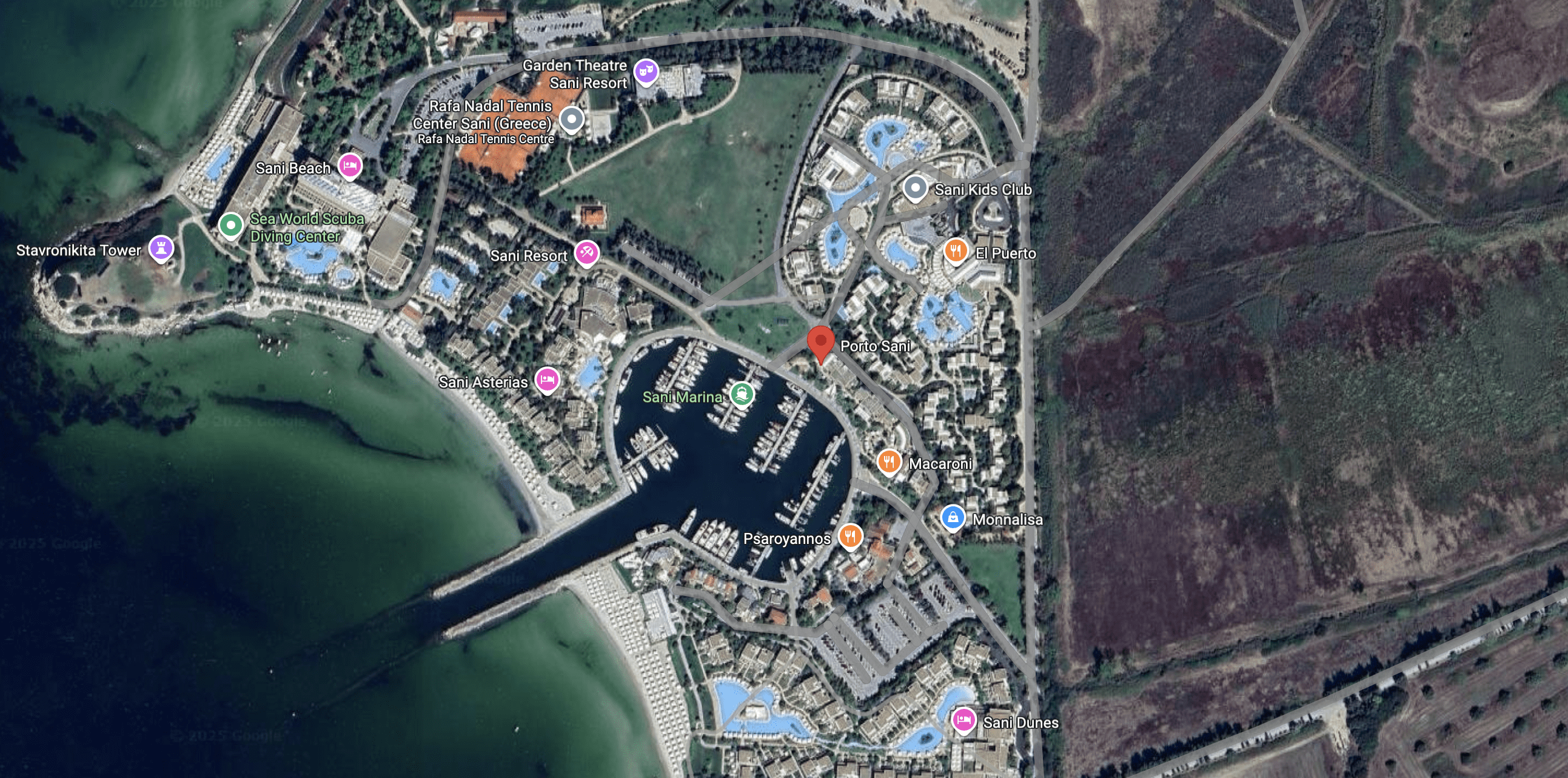Aerial view of a coastal marina with yachts and nearby buildings.