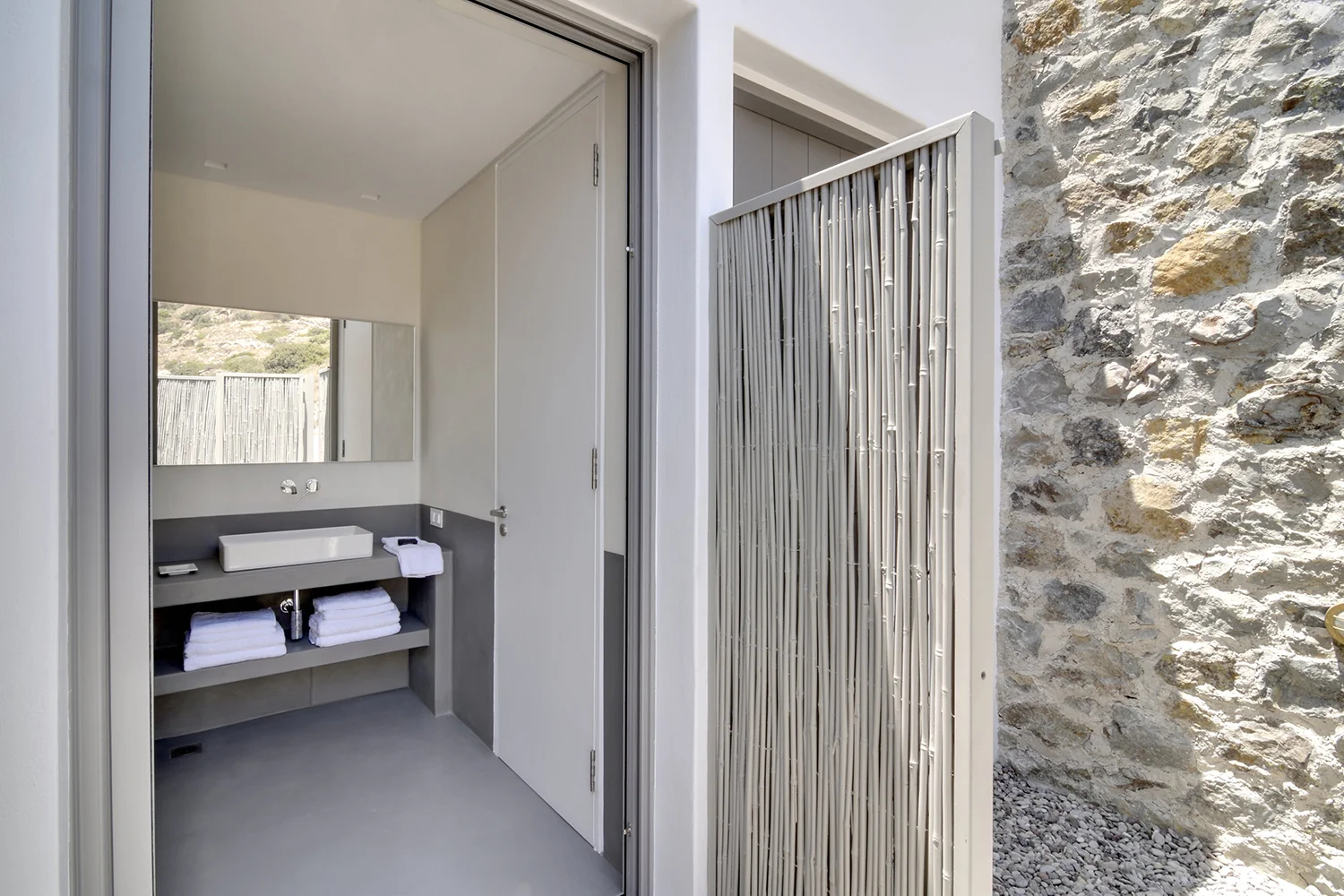 Modern outdoor shower with stone wall and privacy screen.