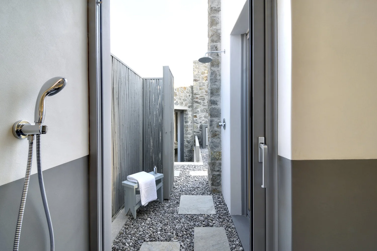 Narrow outdoor passageway with gravel and stone walls.