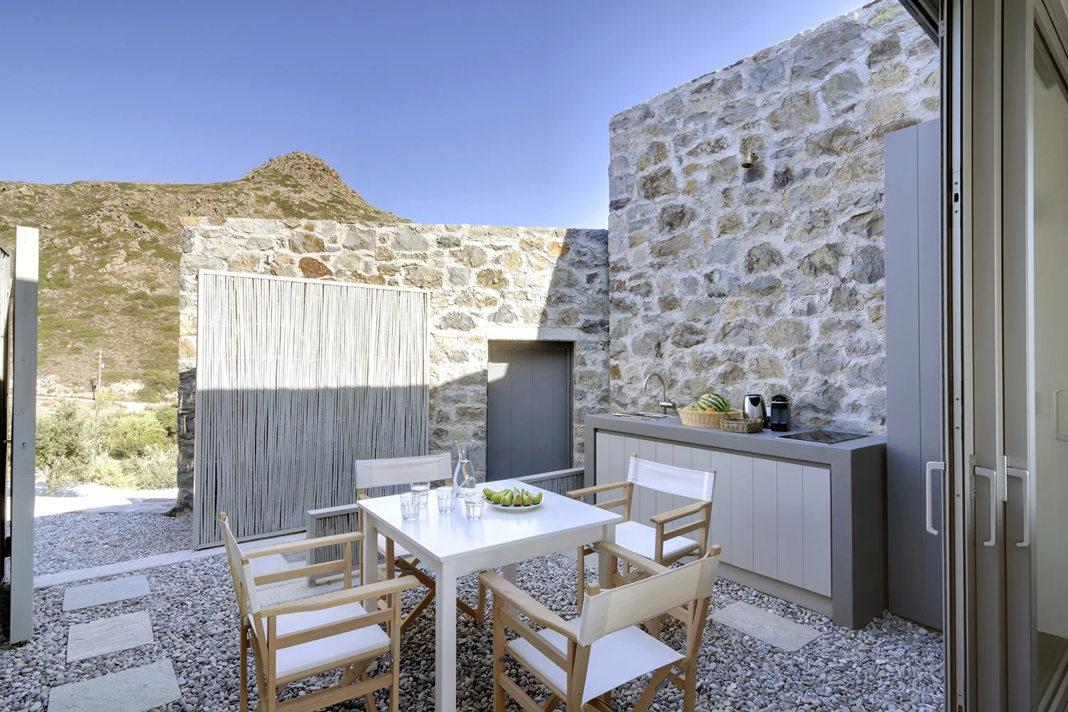Outdoor stone patio with dining set and mountain view.