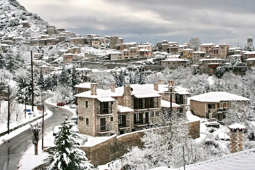 Snow-covered village with traditional stone houses under a cloudy sky.