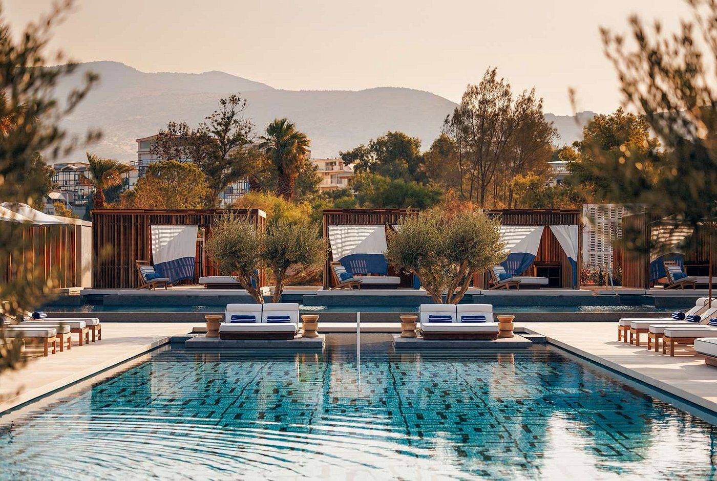 Luxury poolside cabanas with lounge chairs and mountain views at sunset.