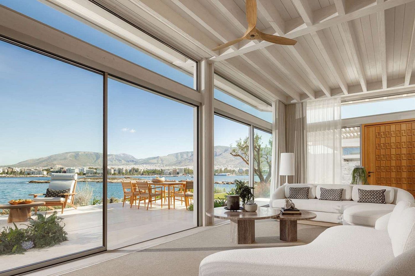 Modern living room with large sliding glass doors overlooking a lake and mountains.