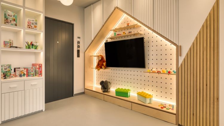 Modern triangular wooden TV unit with shelves and warm lighting.