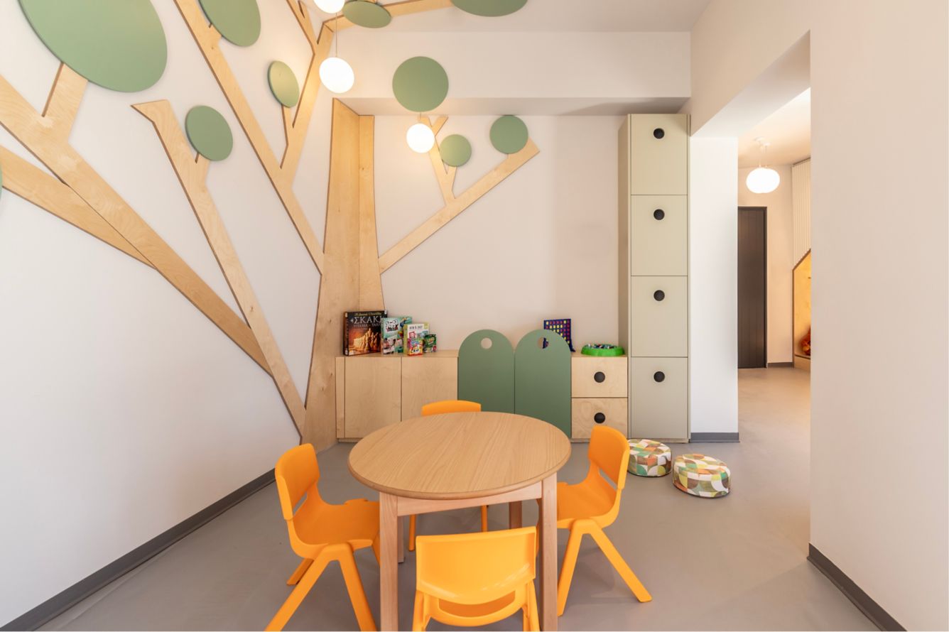 Cozy children's playroom with tree wall art and round table.