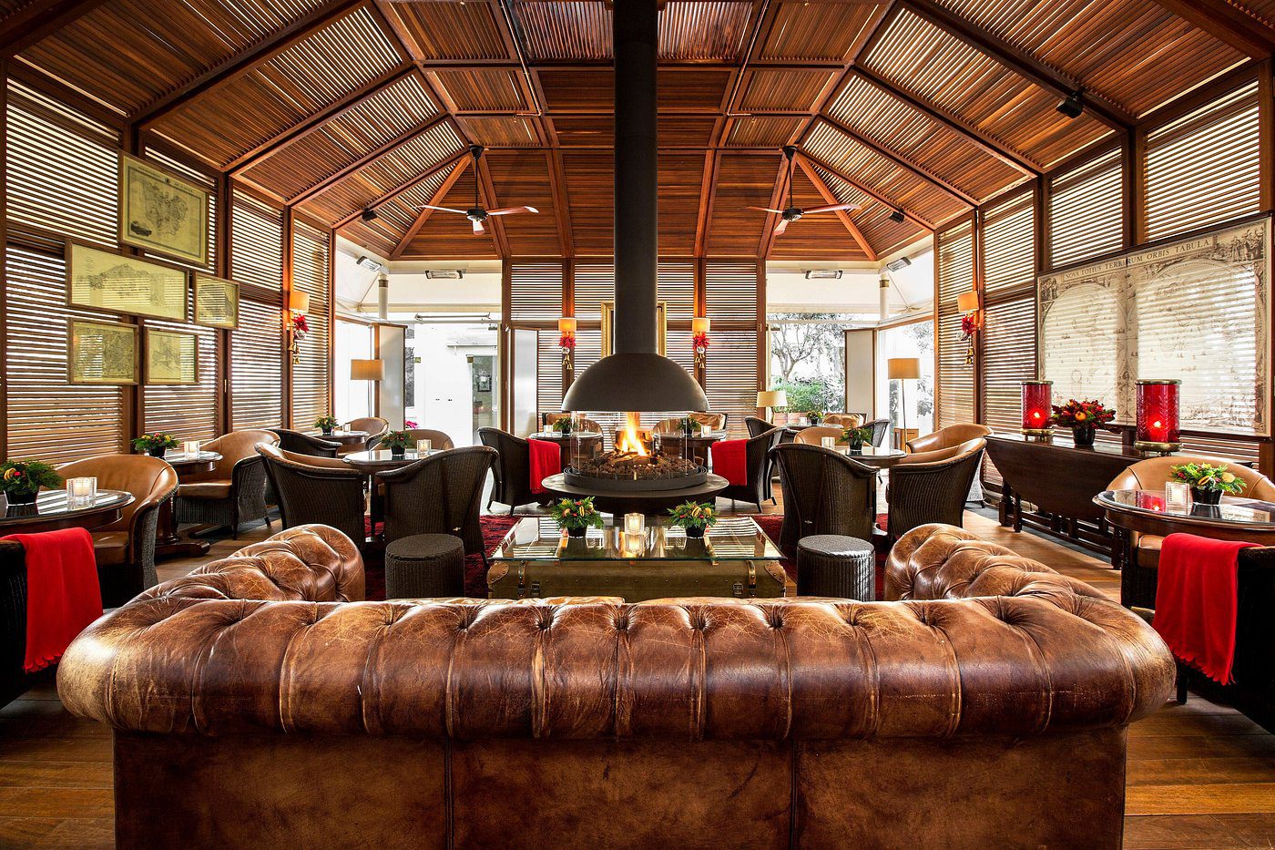Cozy living room with leather sofas and a central fireplace under a wooden ceiling.