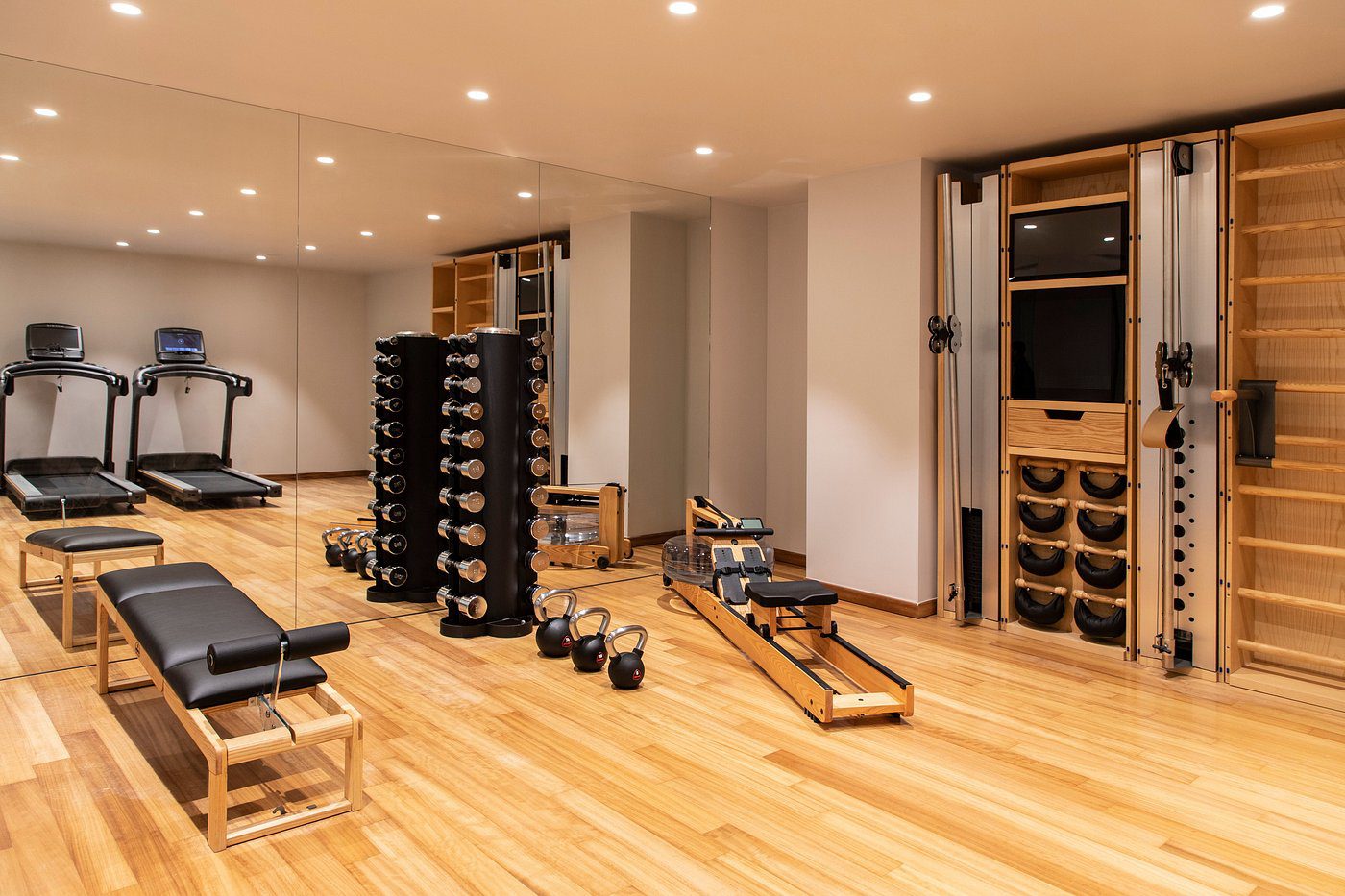 A modern home gym with wooden flooring and various exercise equipment.
