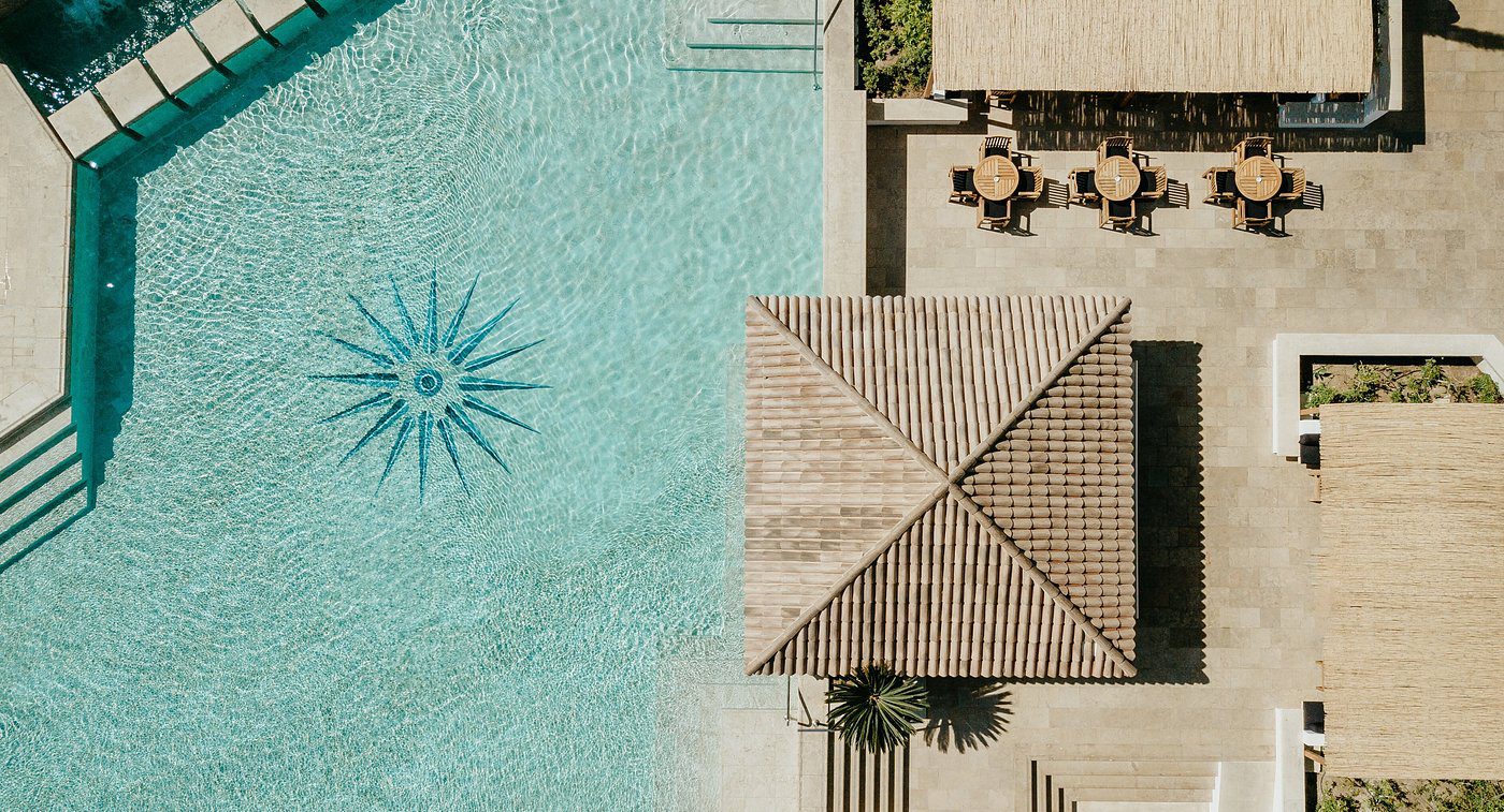 Aerial view of a swimming pool with a sun pattern and adjacent patio area.