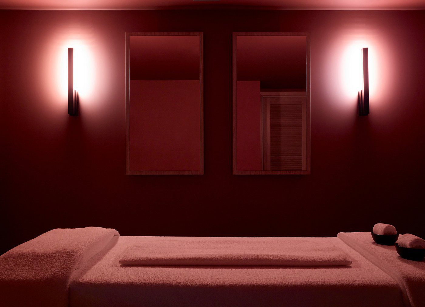 A dimly lit room with warm red lighting and two beds.