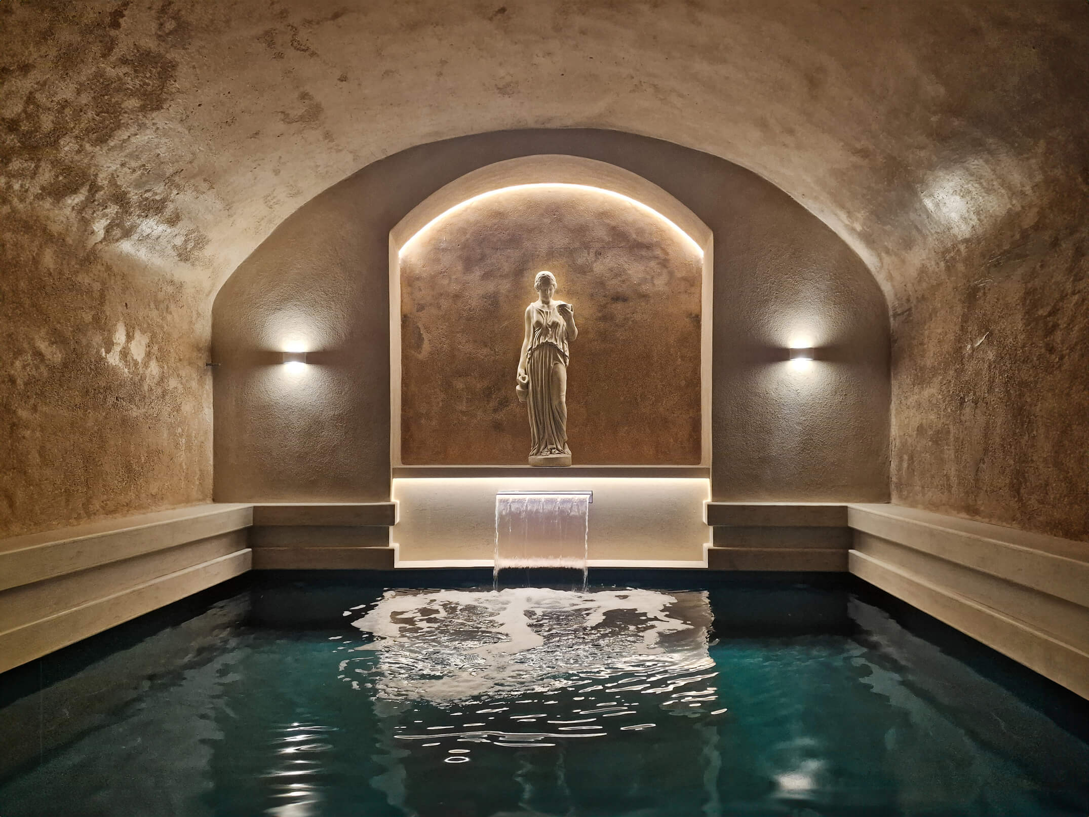 Elegant indoor pool with a classical statue and warm lighting.