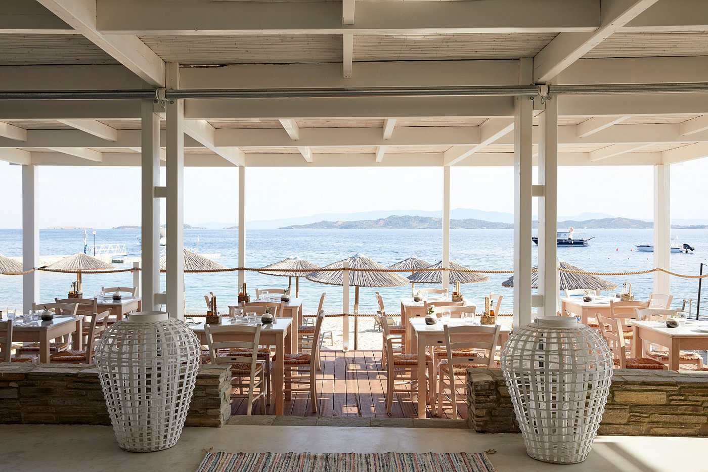 Seaside restaurant with wooden tables and chairs overlooking the ocean.