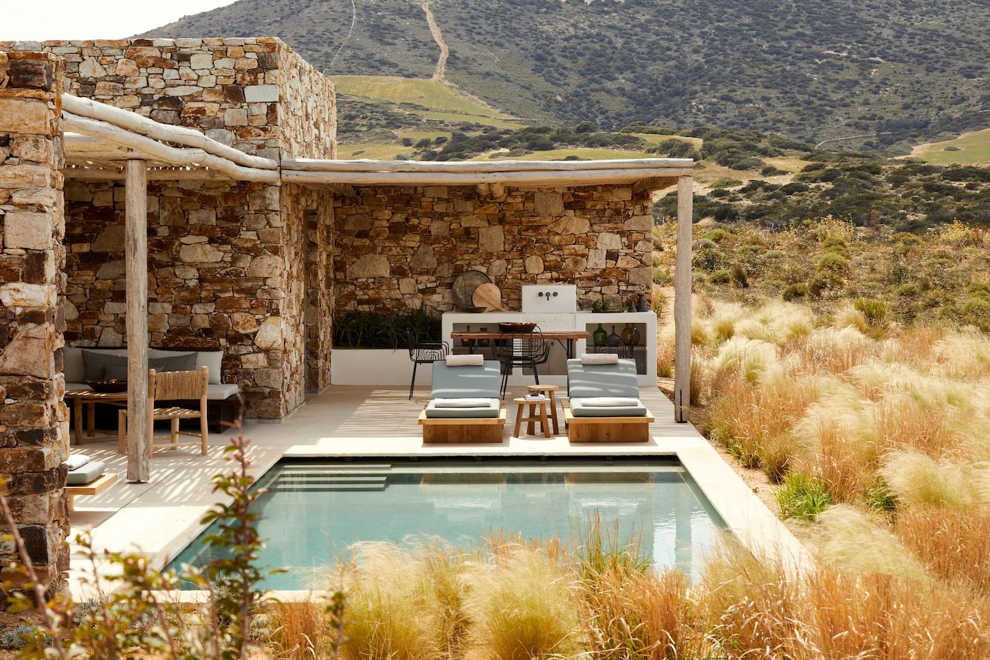 Modern outdoor pool area with stone walls and natural surroundings.