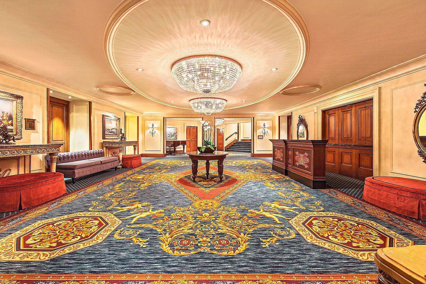 Luxurious hotel lobby with elegant chandelier and ornate carpet.