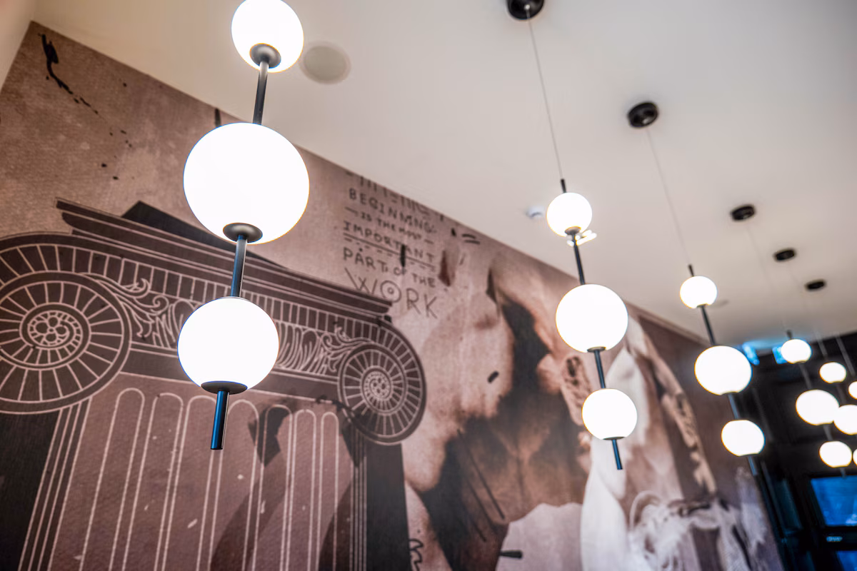 Modern spherical pendant lights hanging in front of a classical wall mural.