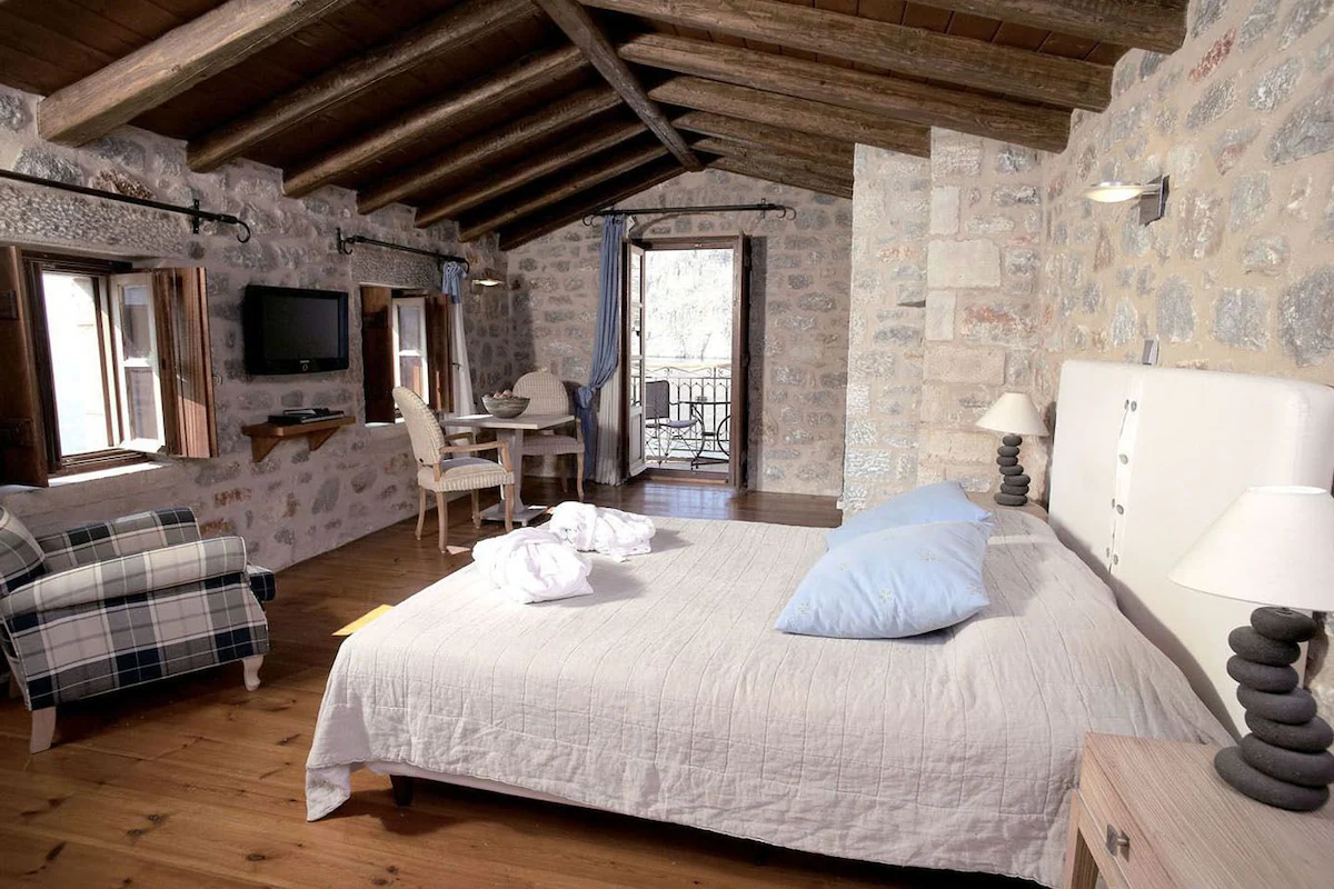 Cozy bedroom with rustic stone walls and wooden ceiling beams.